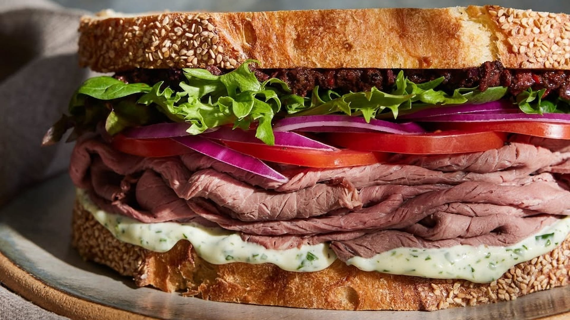 Roast beef sandwich with lettuce, onion, and tomato.