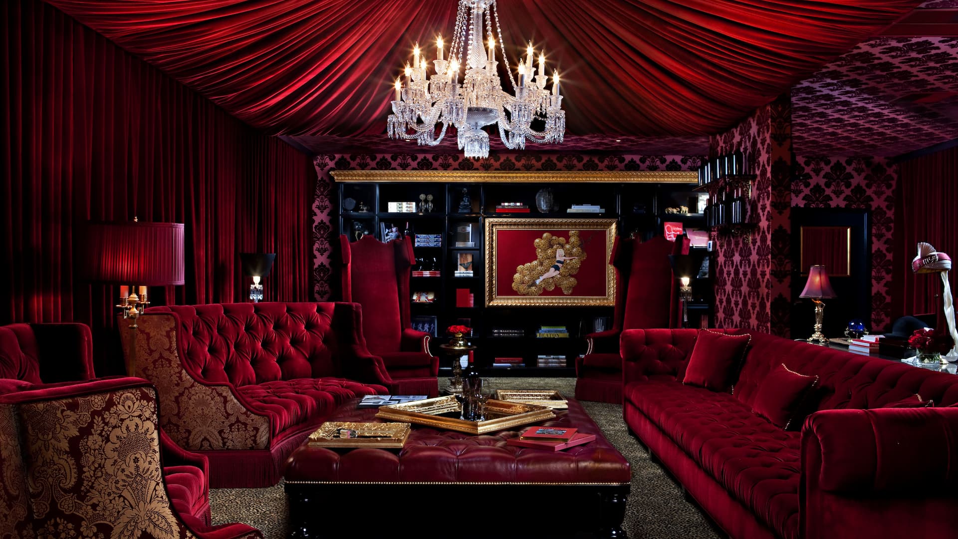 Luxurious red room with chandelier and seating area.