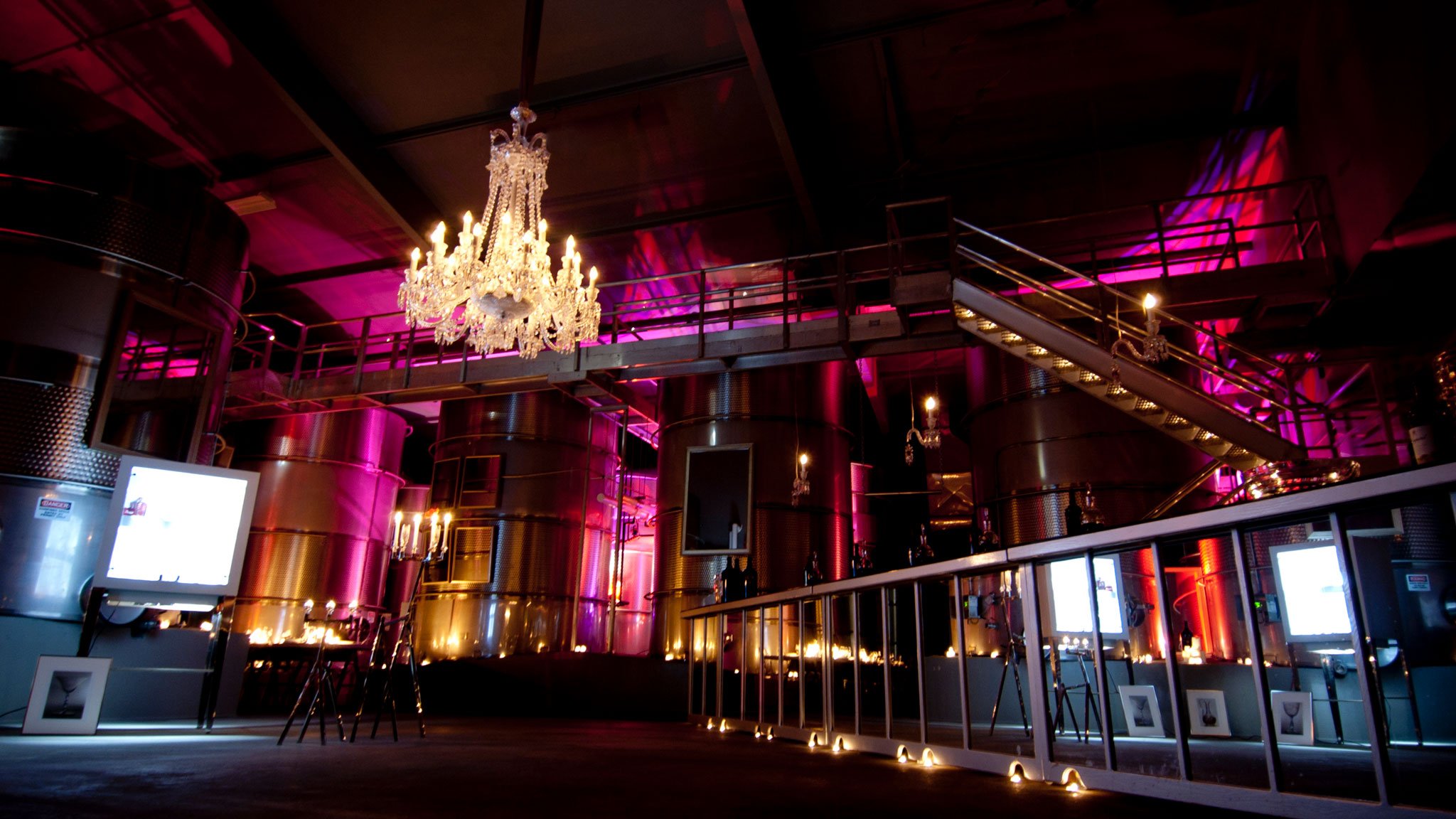 Industrial space with chandelier and pink lighting.