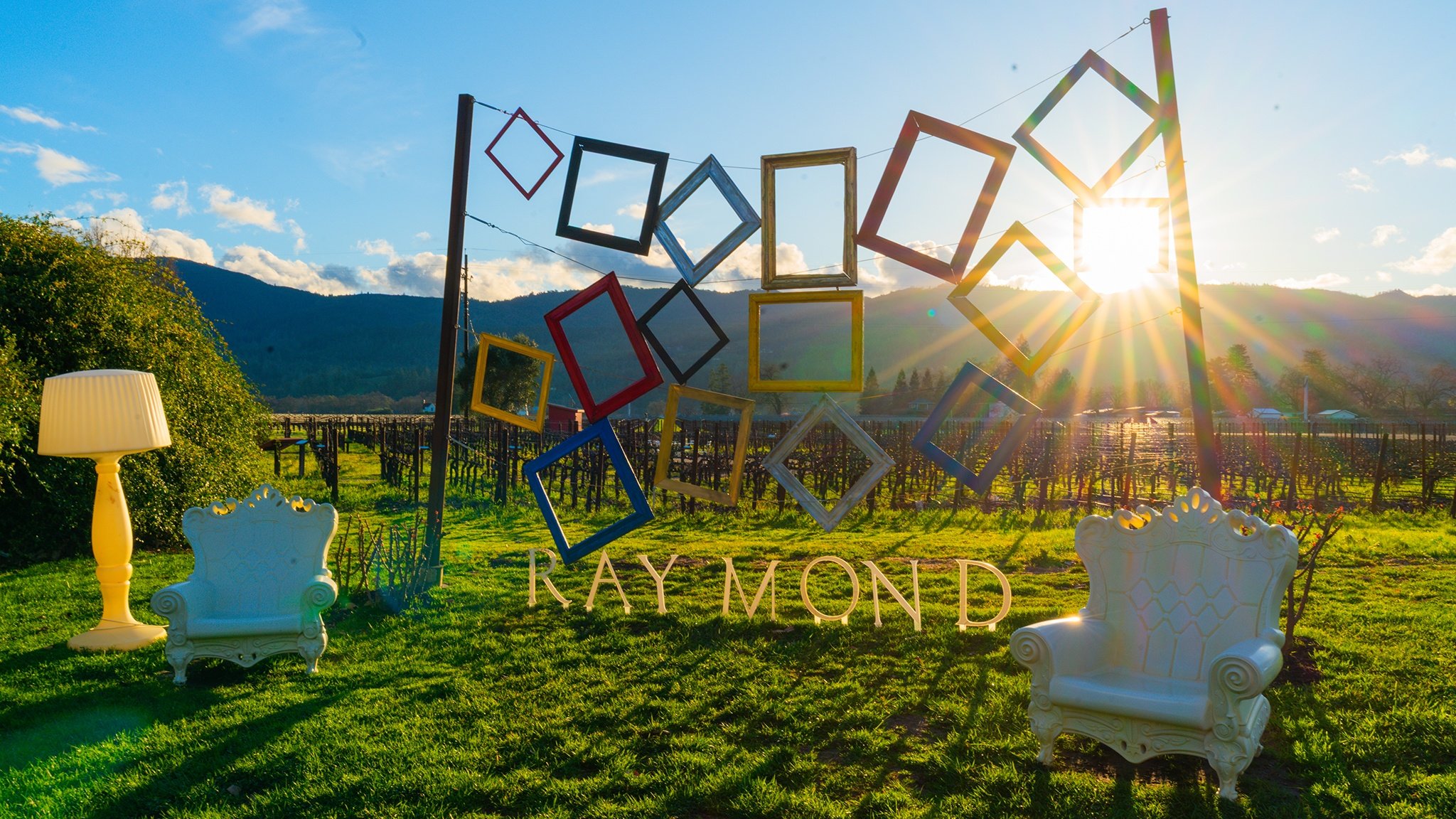 Art installation with frames in vineyard, sun setting.