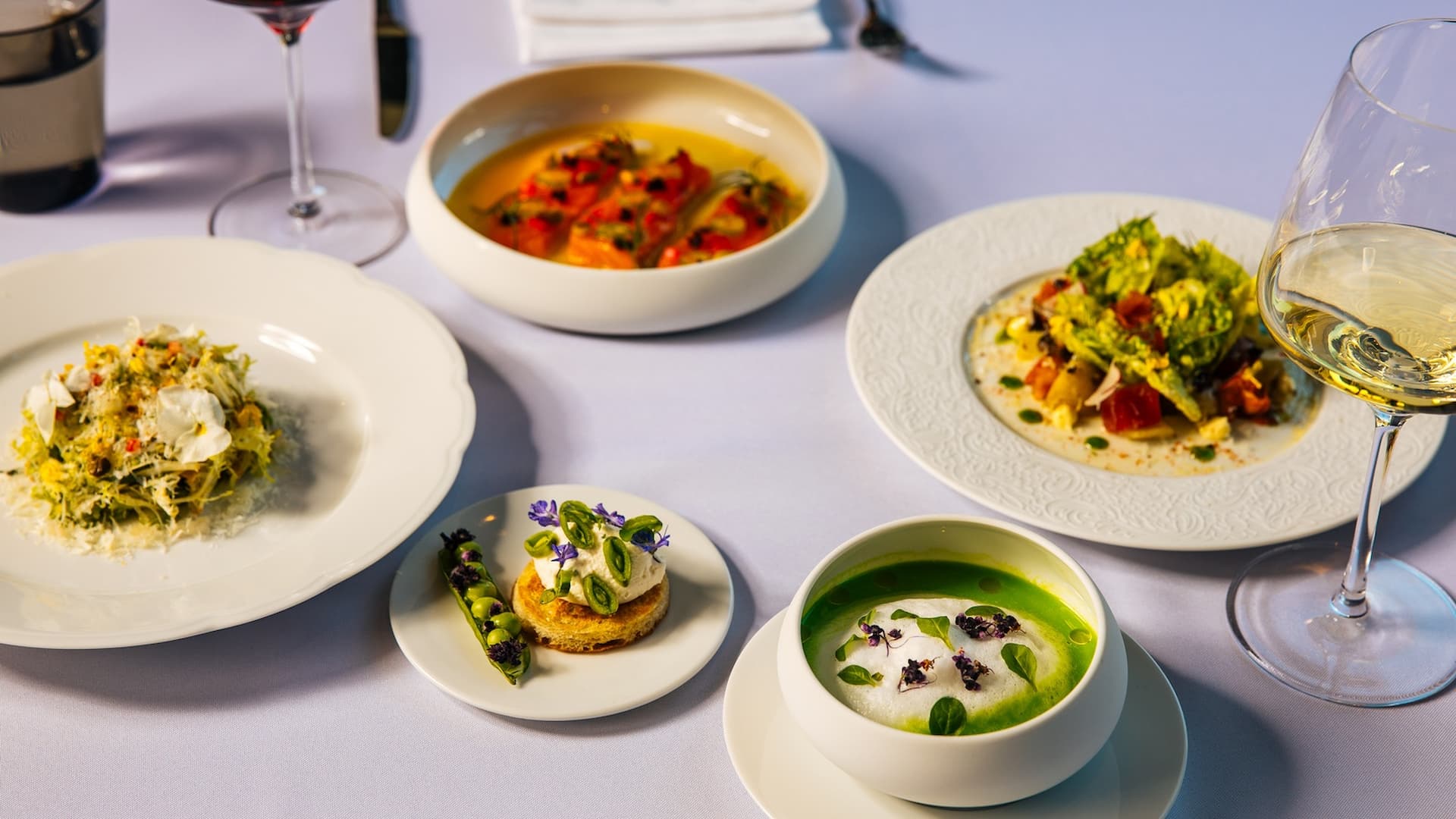 Gourmet dishes with wine glasses on elegant table.