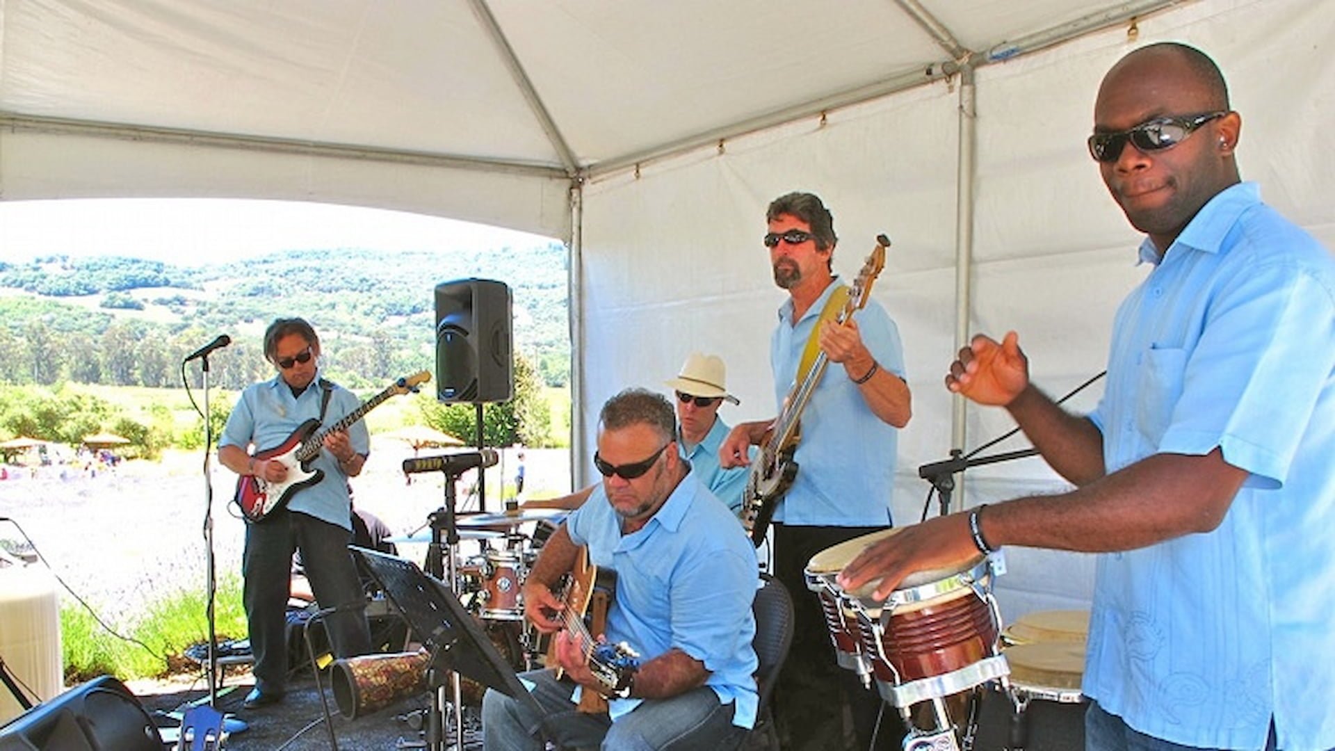 Band performing outdoors under a tent.