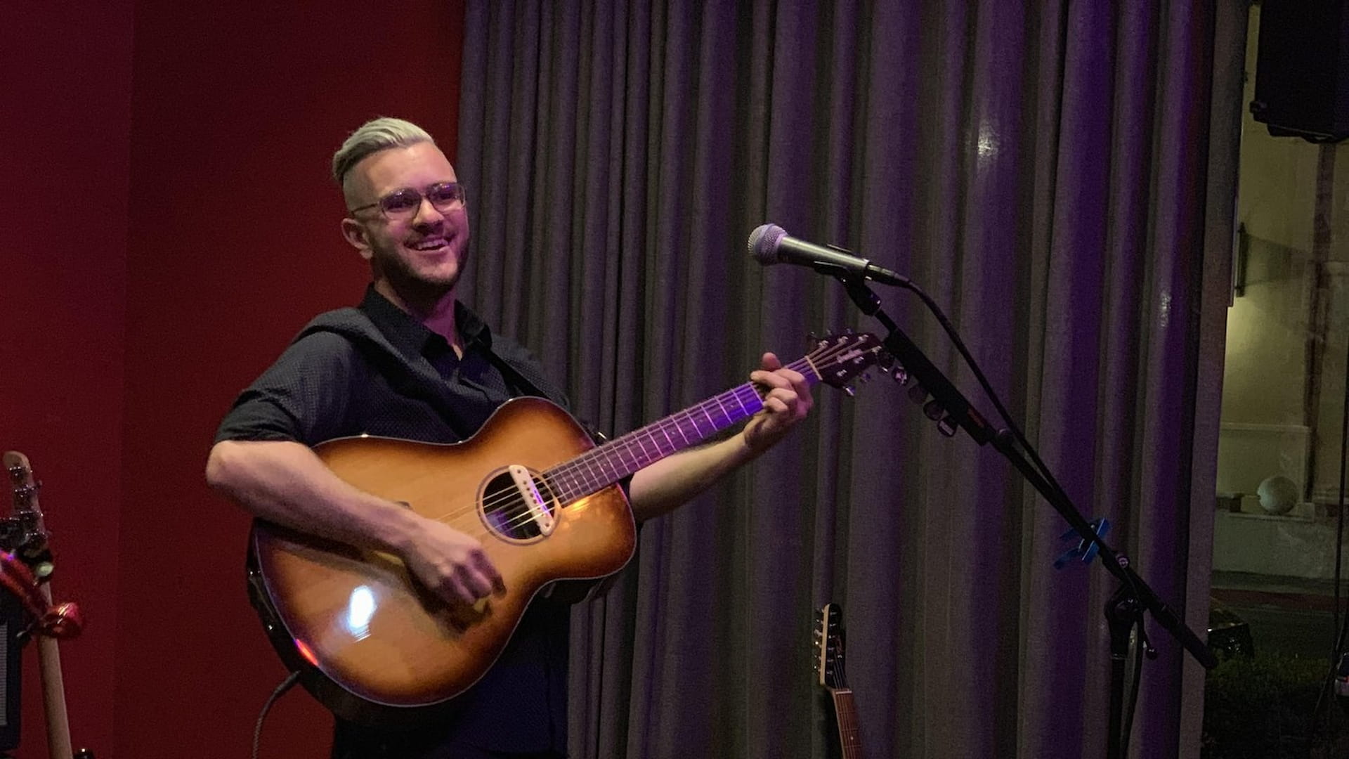 Man playing acoustic guitar on stage.