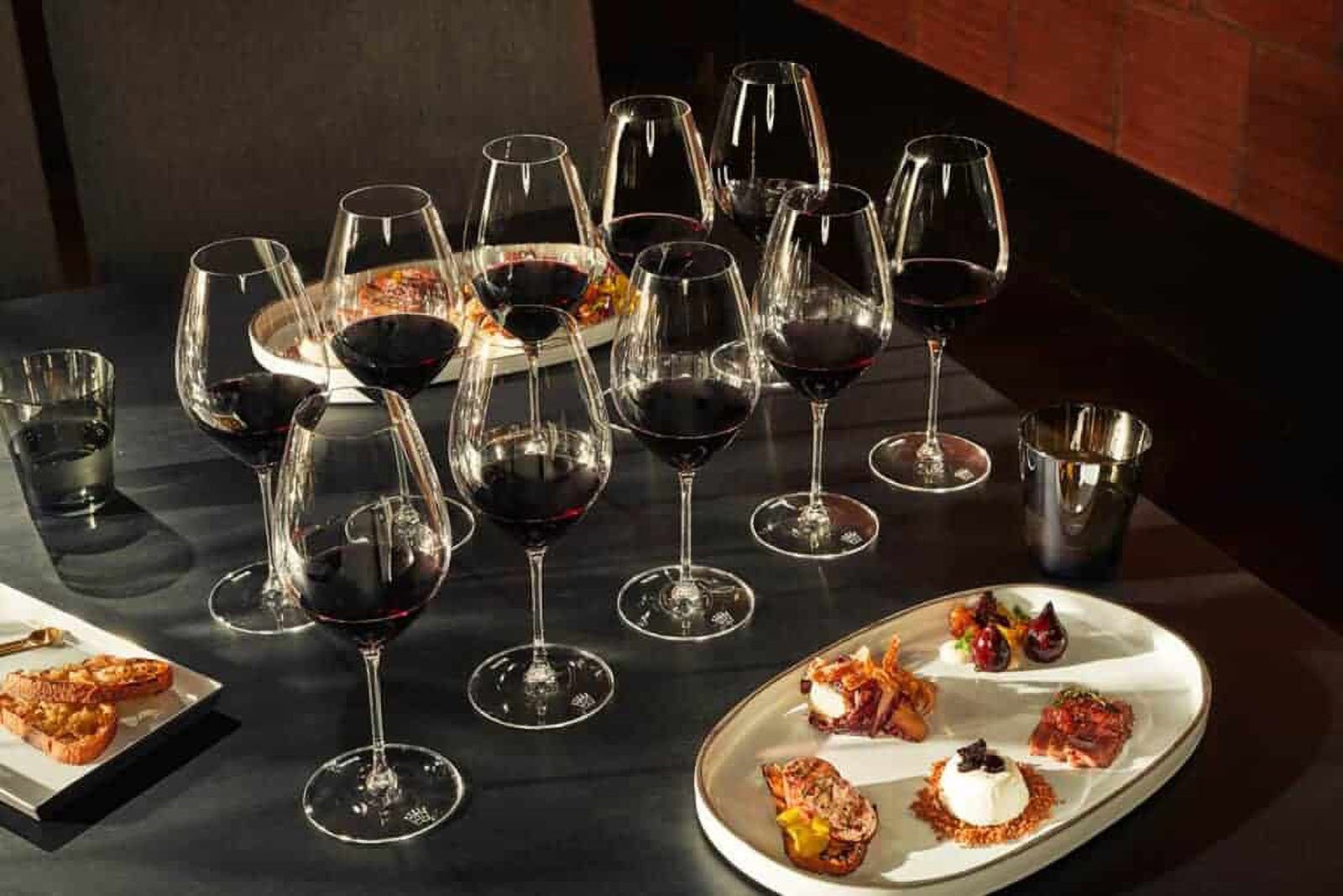 Red wine glasses with assorted appetizers on table.