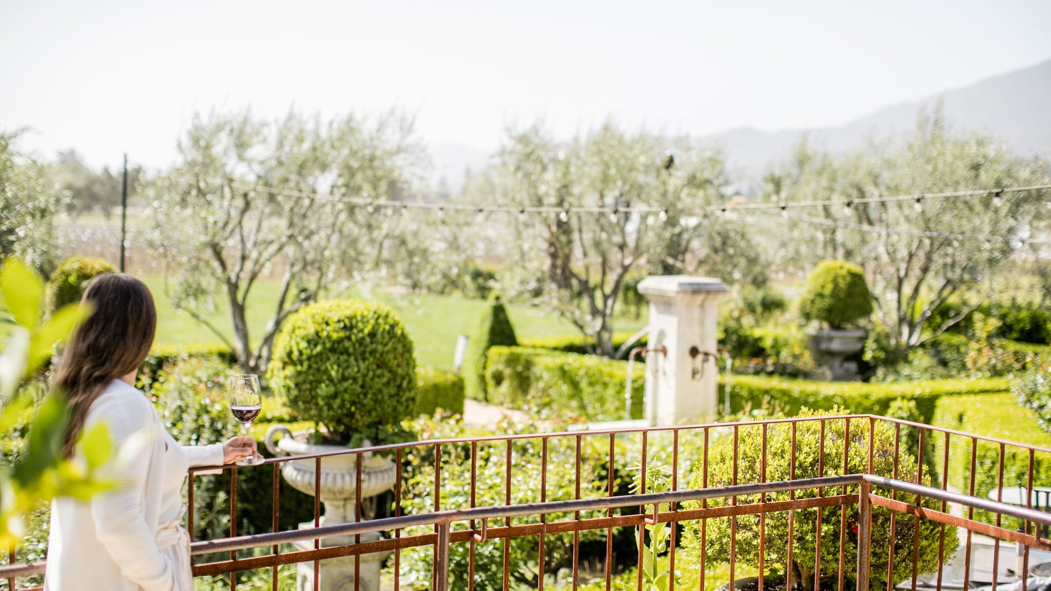 Woman enjoying wine on garden terrace