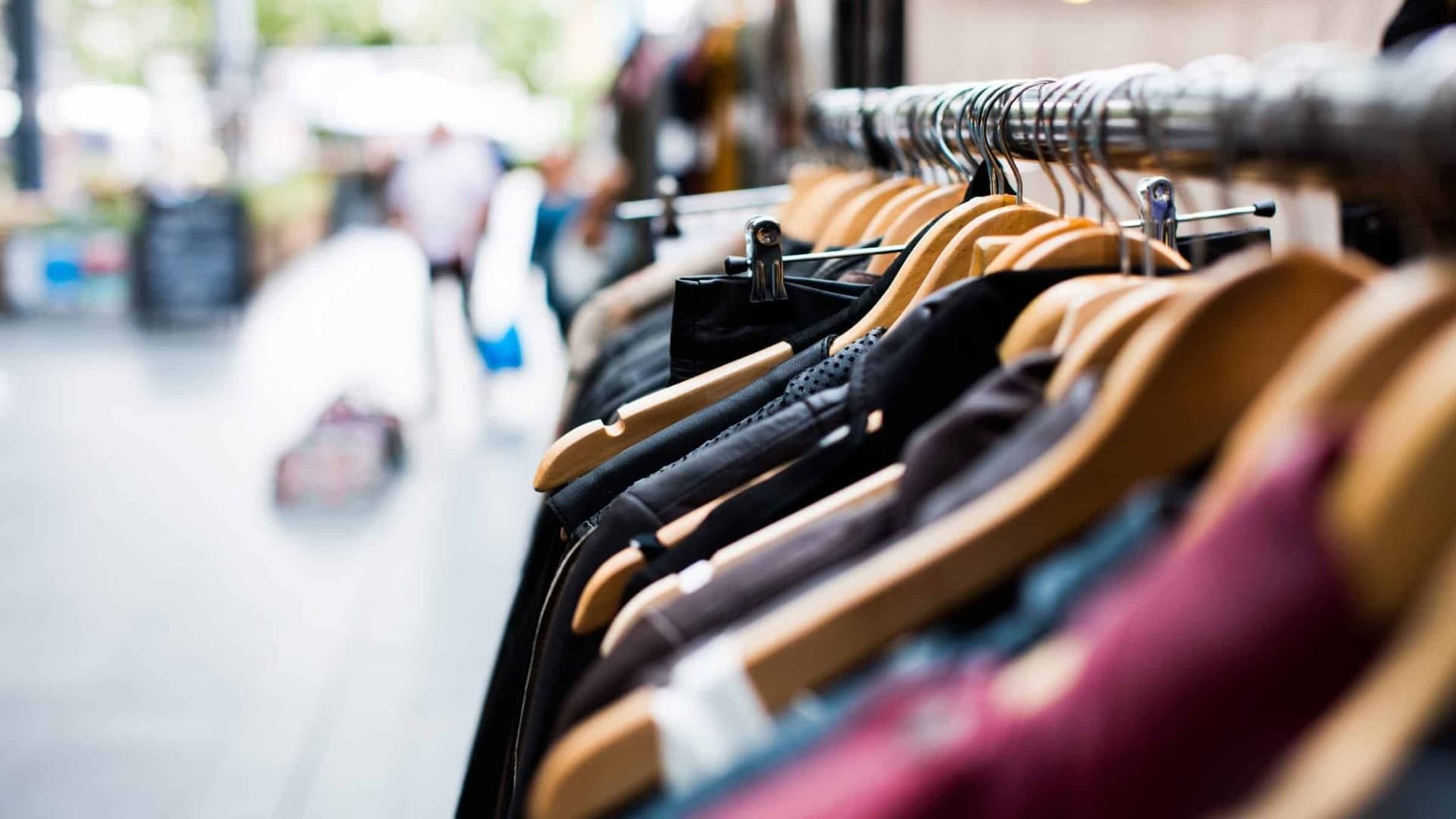 Clothes hanging on wooden hangers in a store.