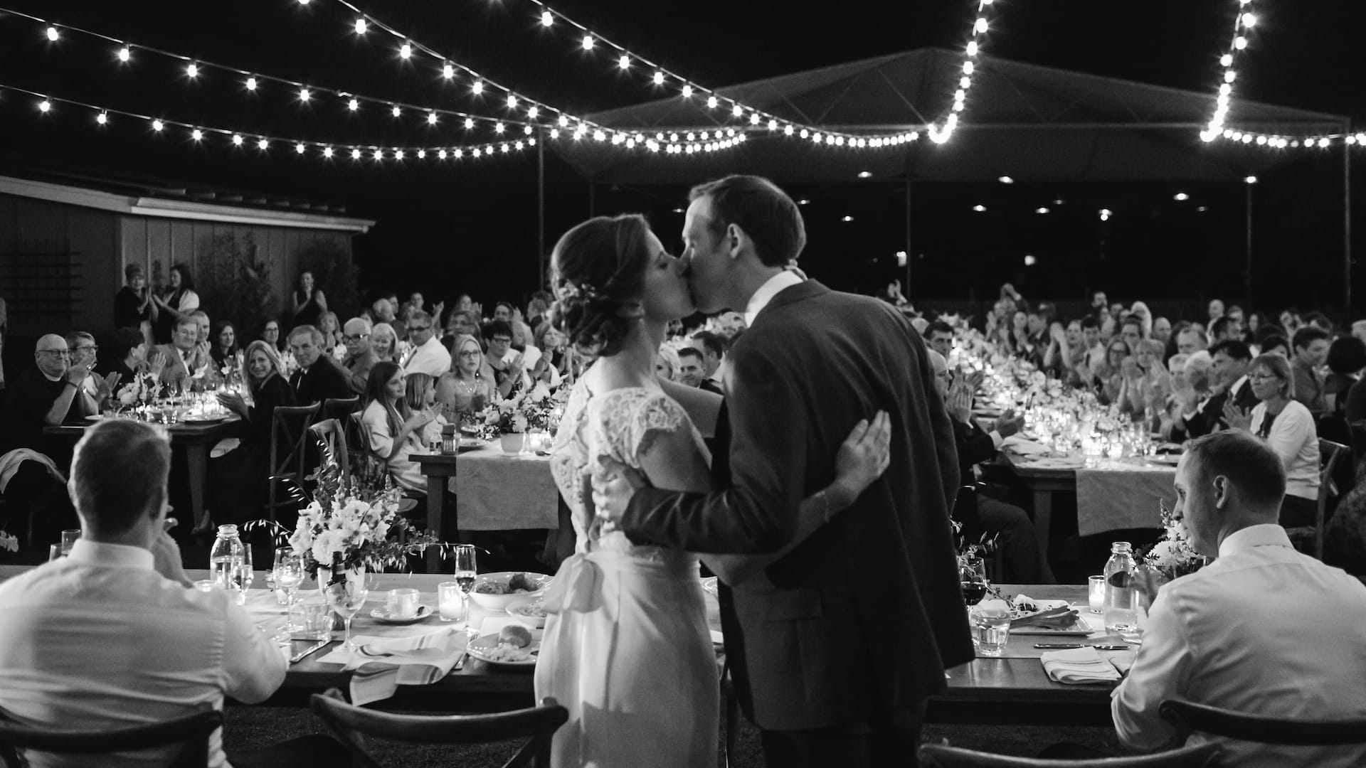 Bride and groom kissing at night wedding reception.