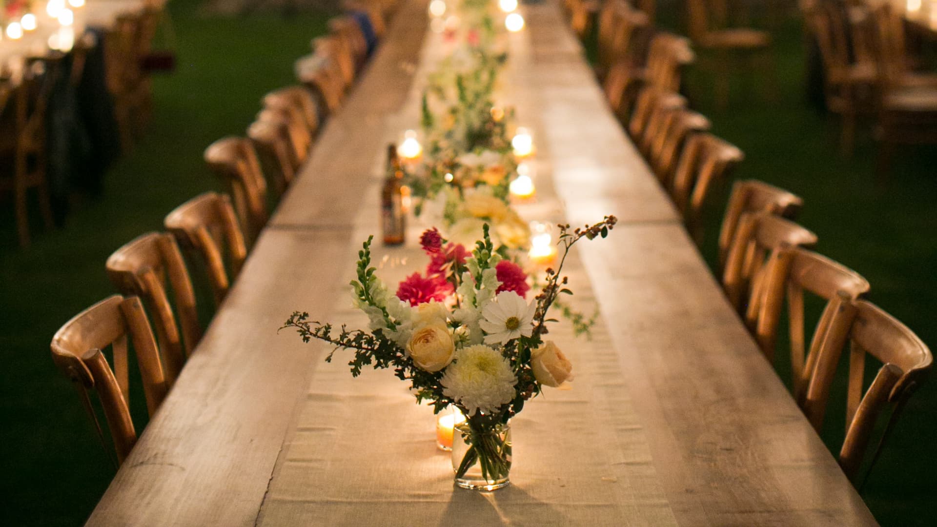 Long table with flowers and candles at night.