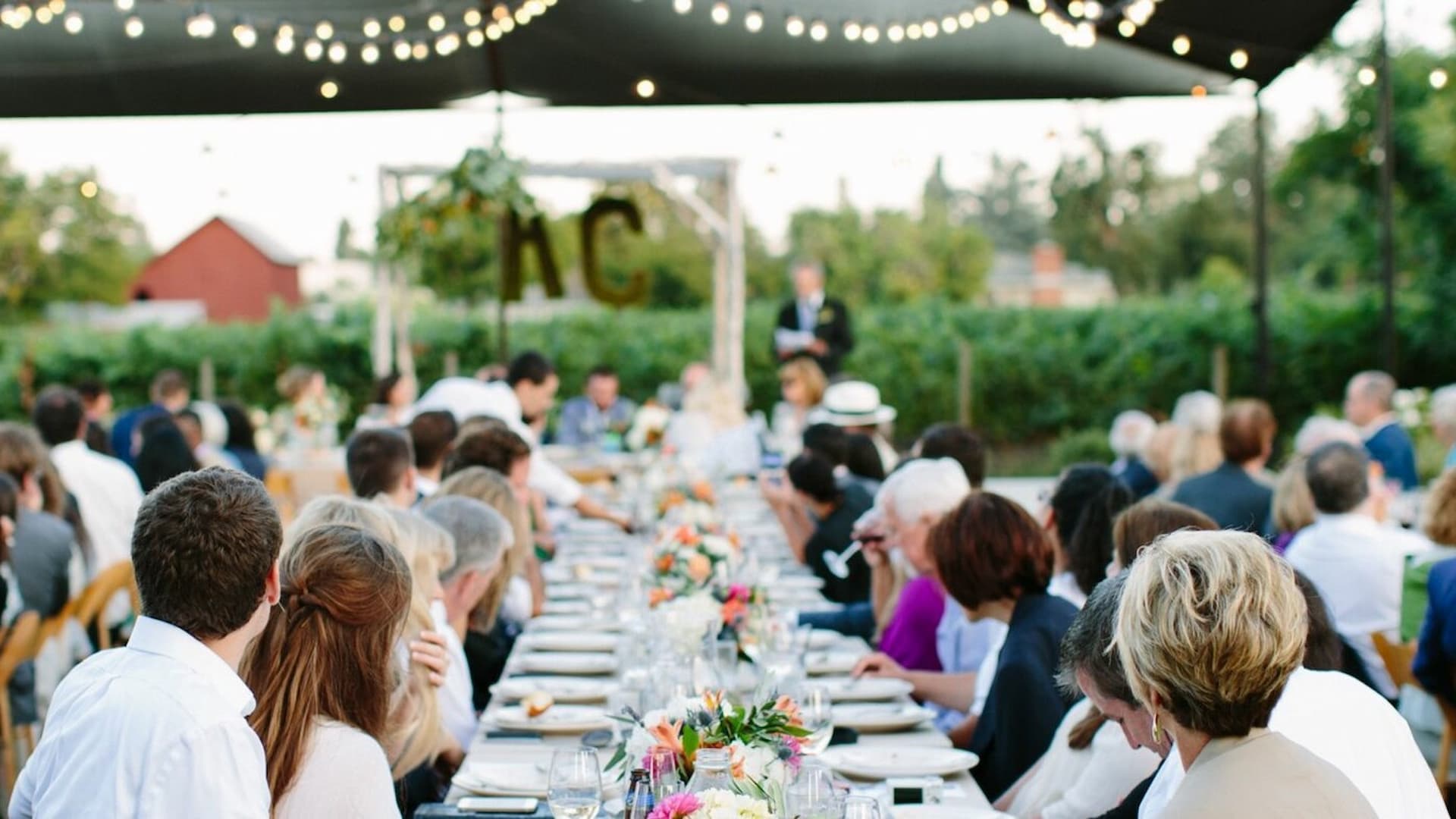 Outdoor wedding reception with guests seated.
