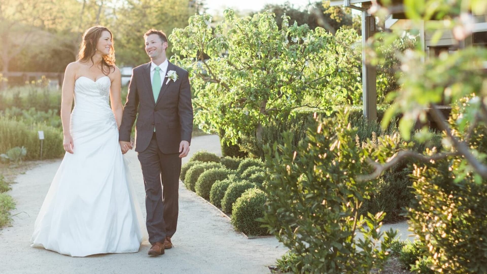 Bride and groom walking in a garden.