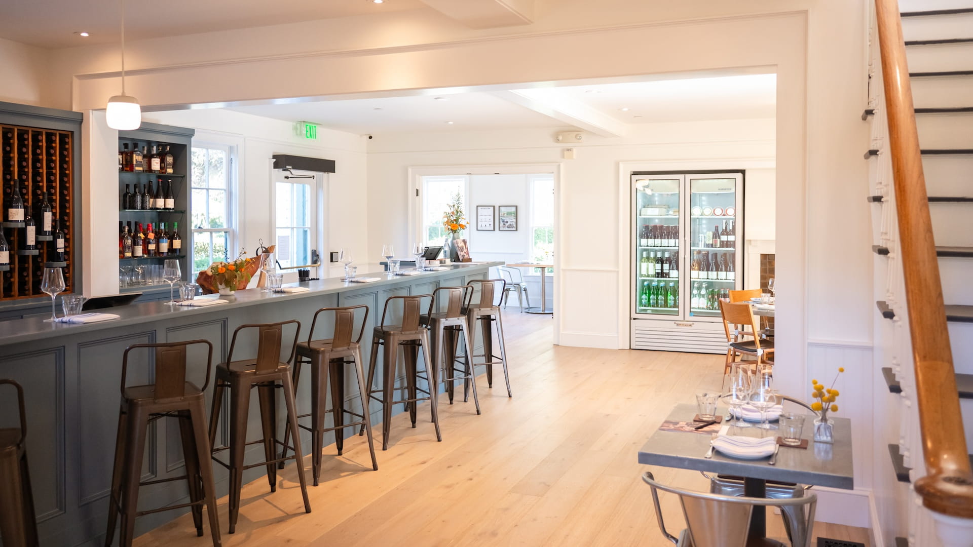 Modern bar interior with stools and wine display.