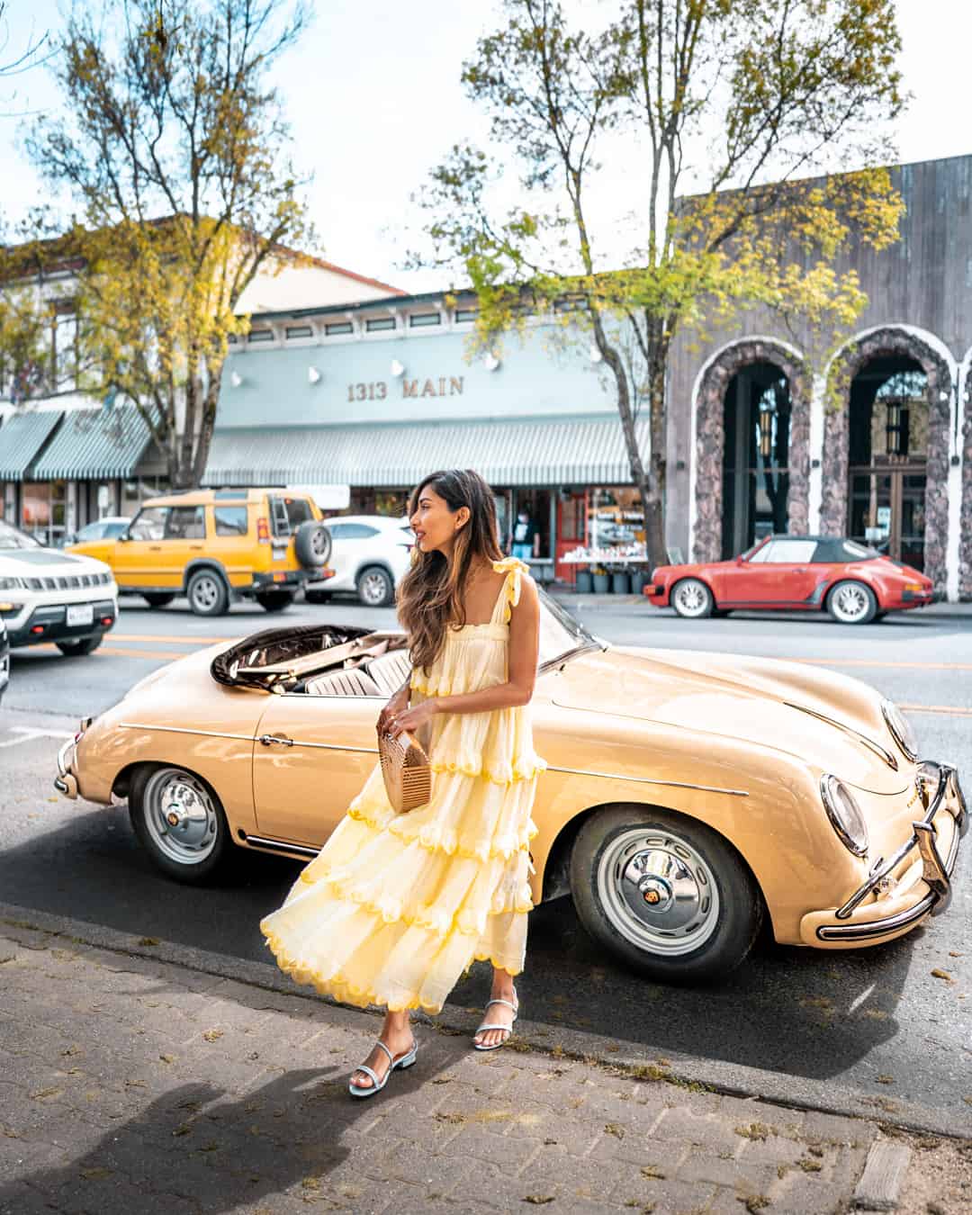 Woman in yellow dress with vintage convertible car.