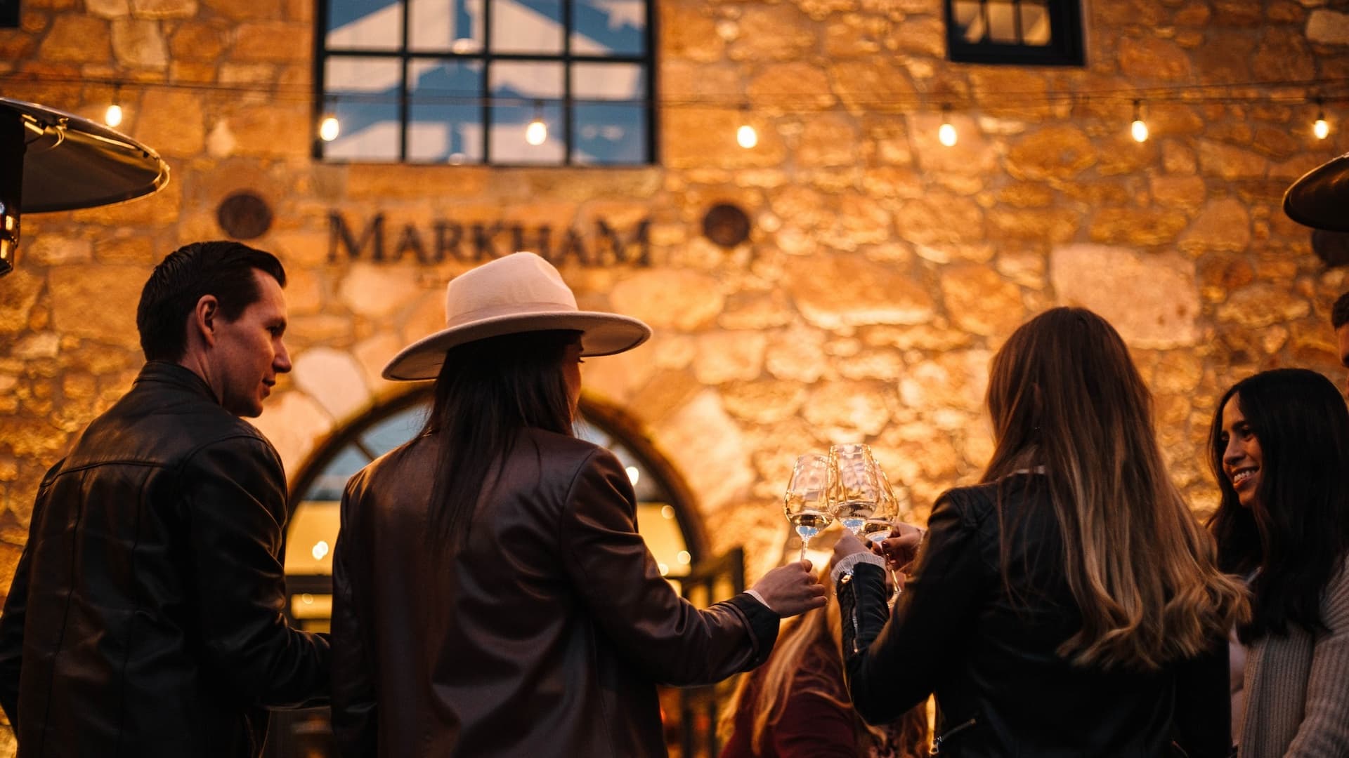 Group toasting outside winery with lights.