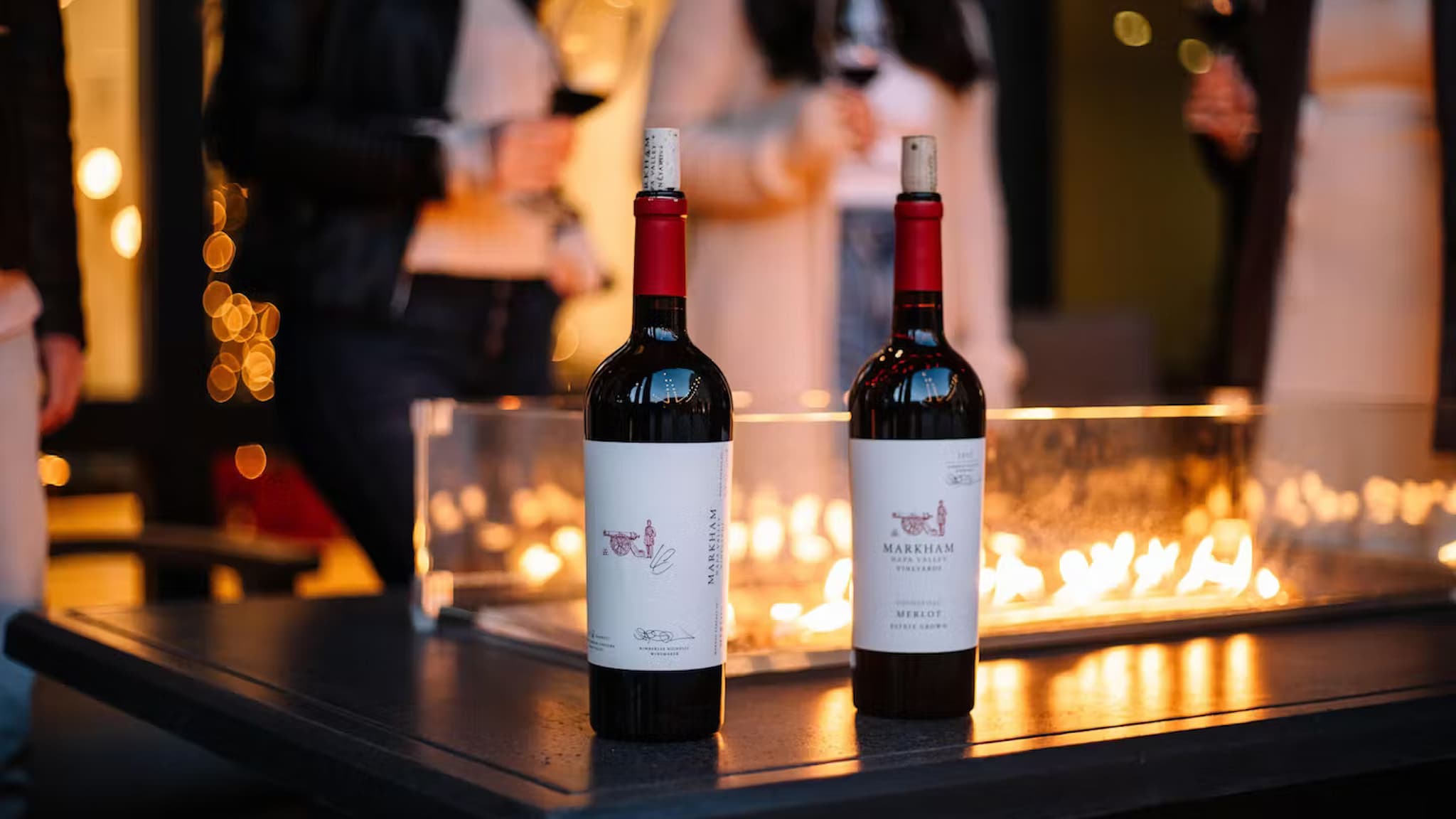 Wine bottles on table with people in background.