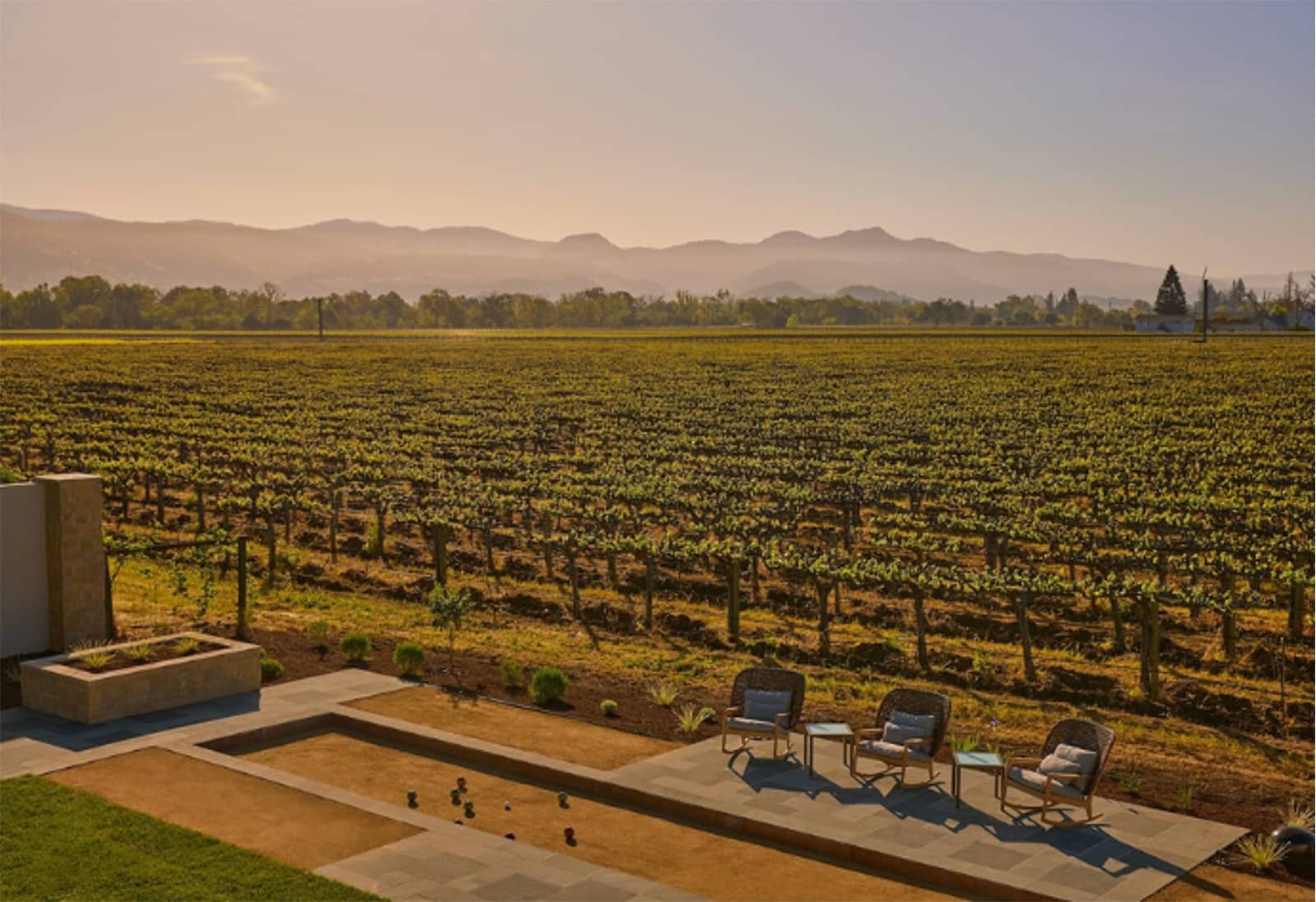 Sunset over vineyard with patio chairs in foreground.