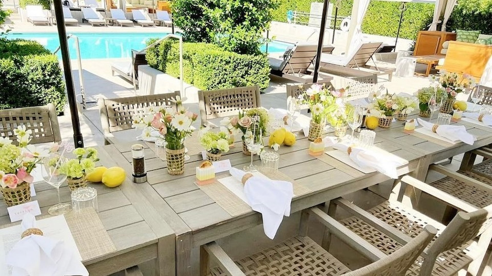 Elegant poolside dining table set with flowers and lemons.