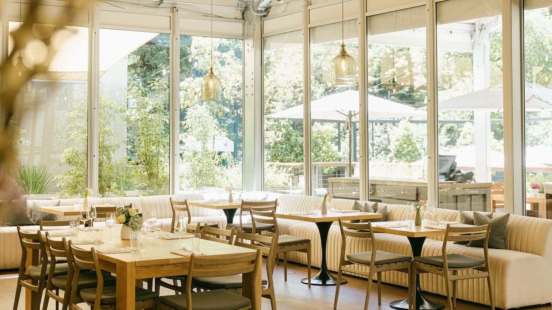Bright airy restaurant with glass walls and wooden tables.