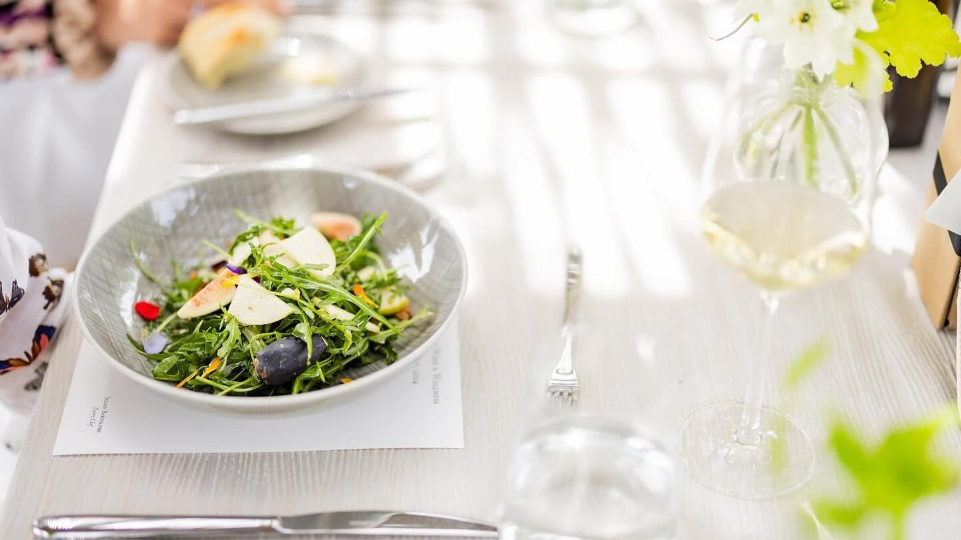 Fresh green salad with apples and wine glass.