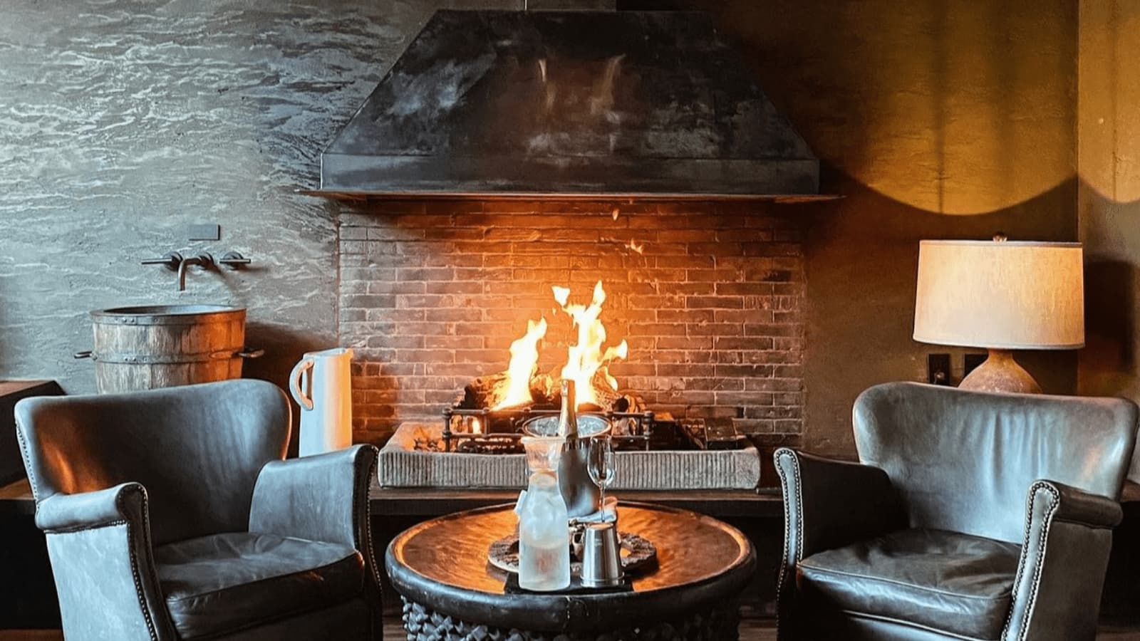 Cozy fireplace room with chairs and table.