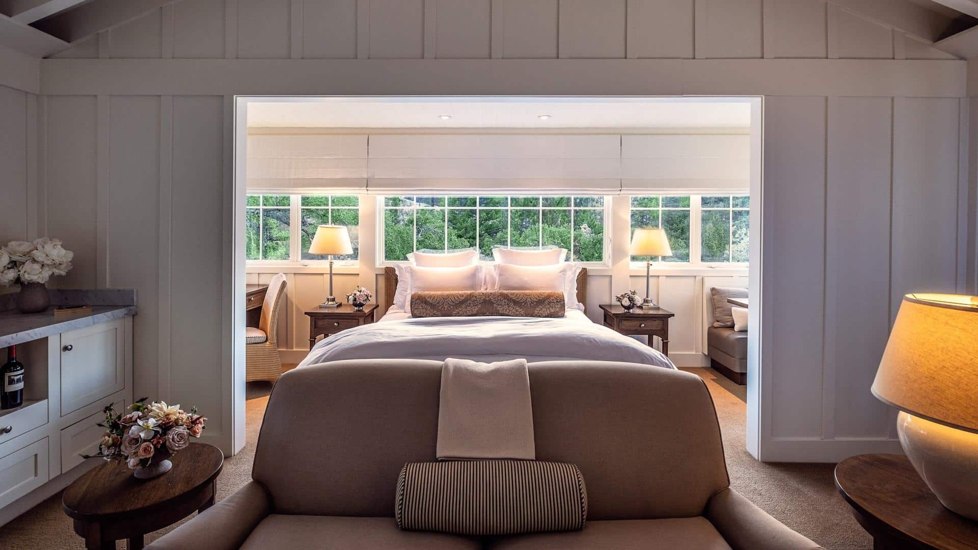 Cozy bedroom with lamps and large windows.