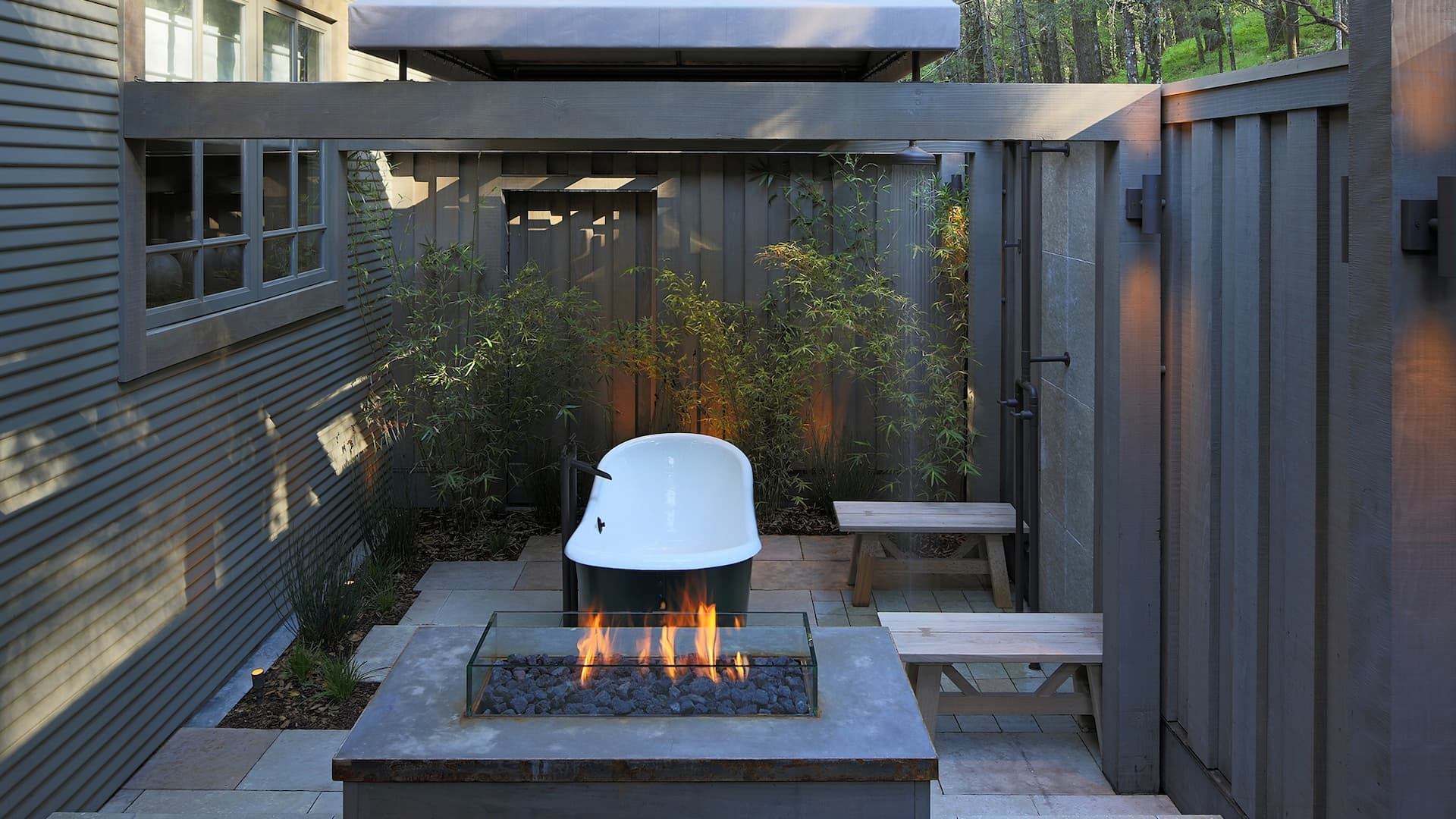 Outdoor bathtub with fire pit and bamboo.