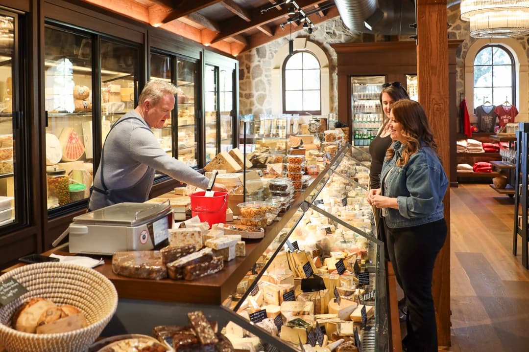 Cheesemonger serving customers in artisan cheese shop