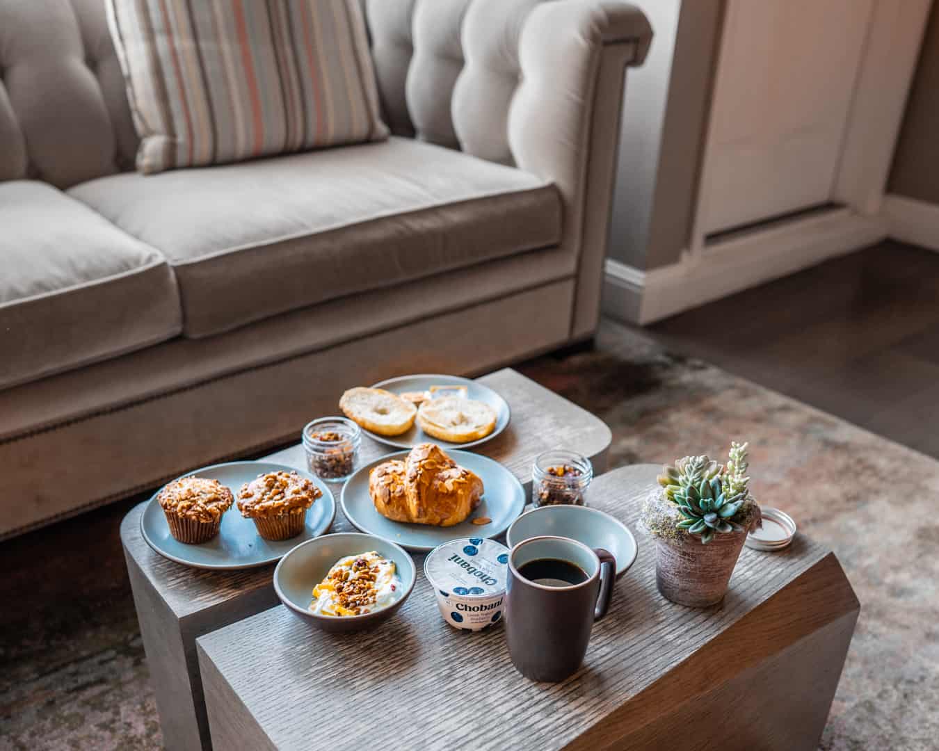Breakfast on coffee table with muffins and coffee.