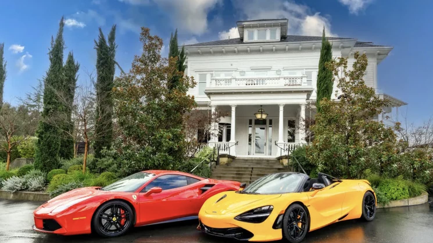 Red and yellow sports cars in front of mansion.