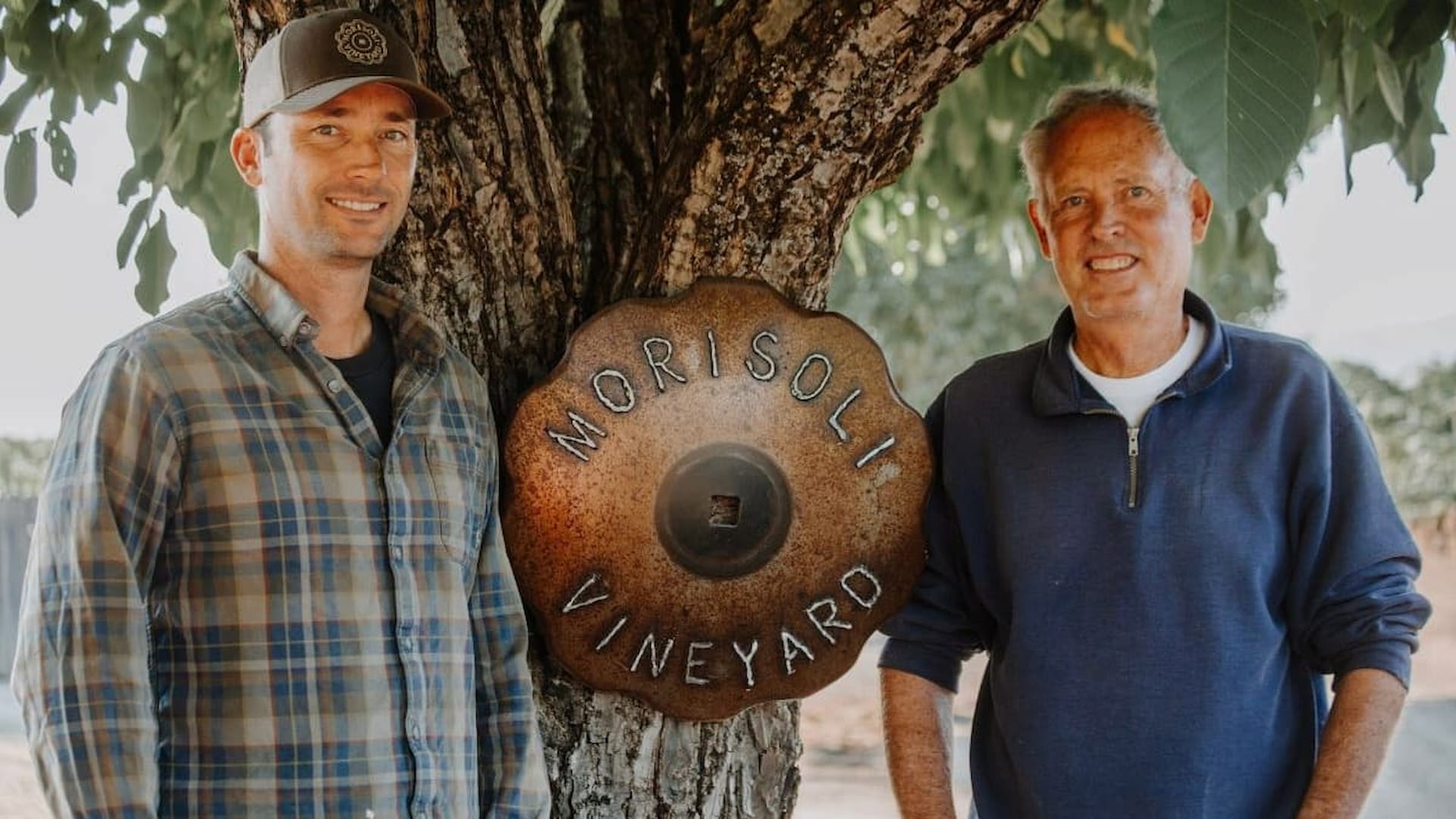 Two men beside Morisoli Vineyard sign