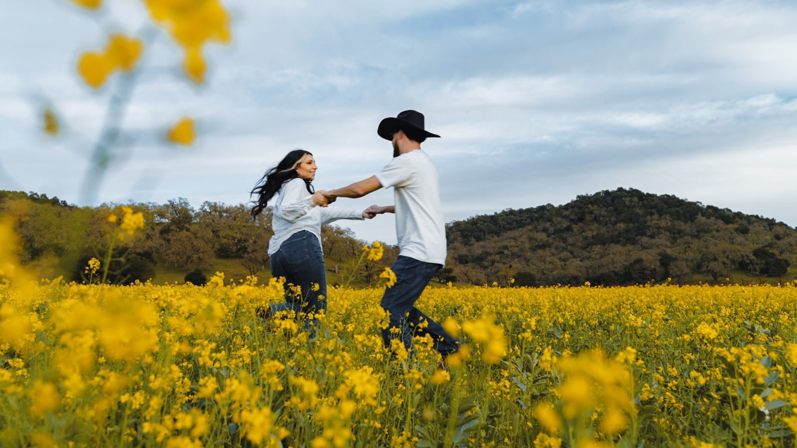 Couple dancing in yellow flower field.