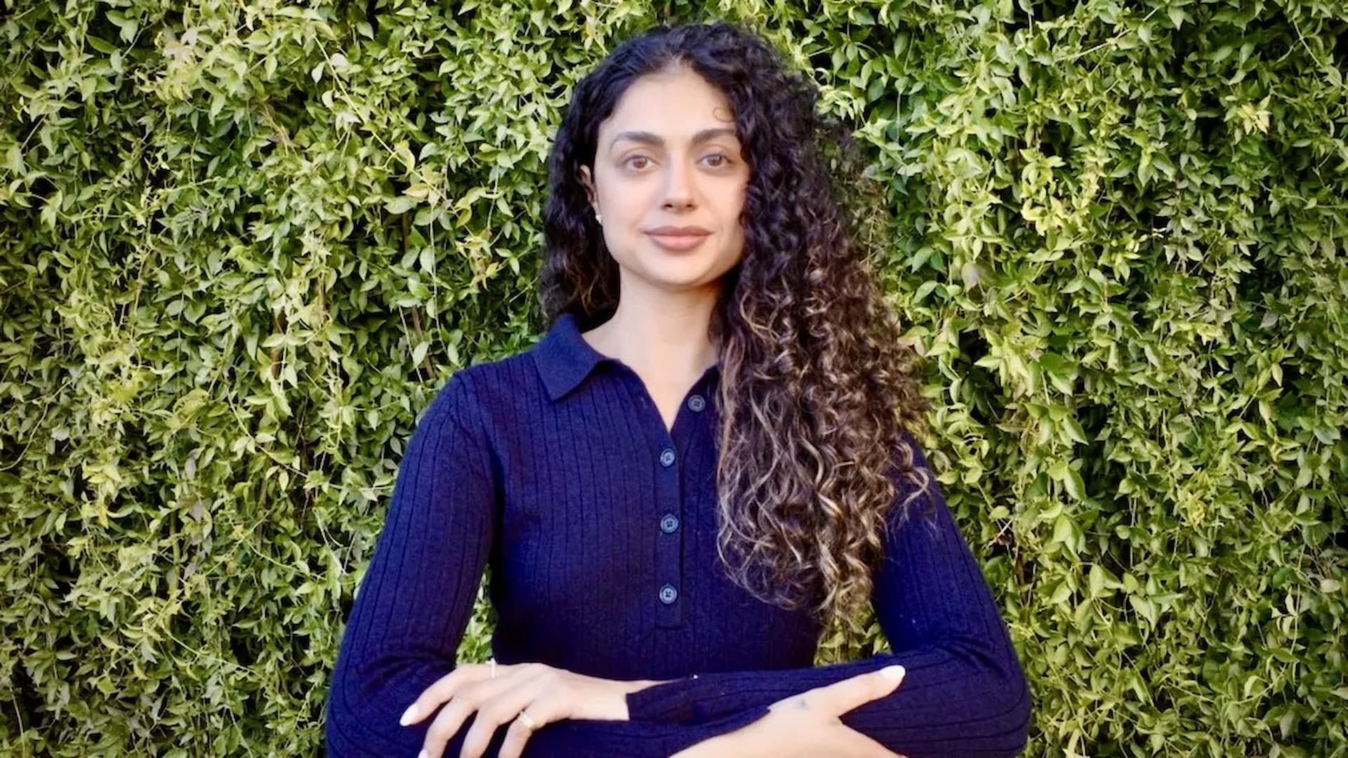 Person in front of leafy green background.