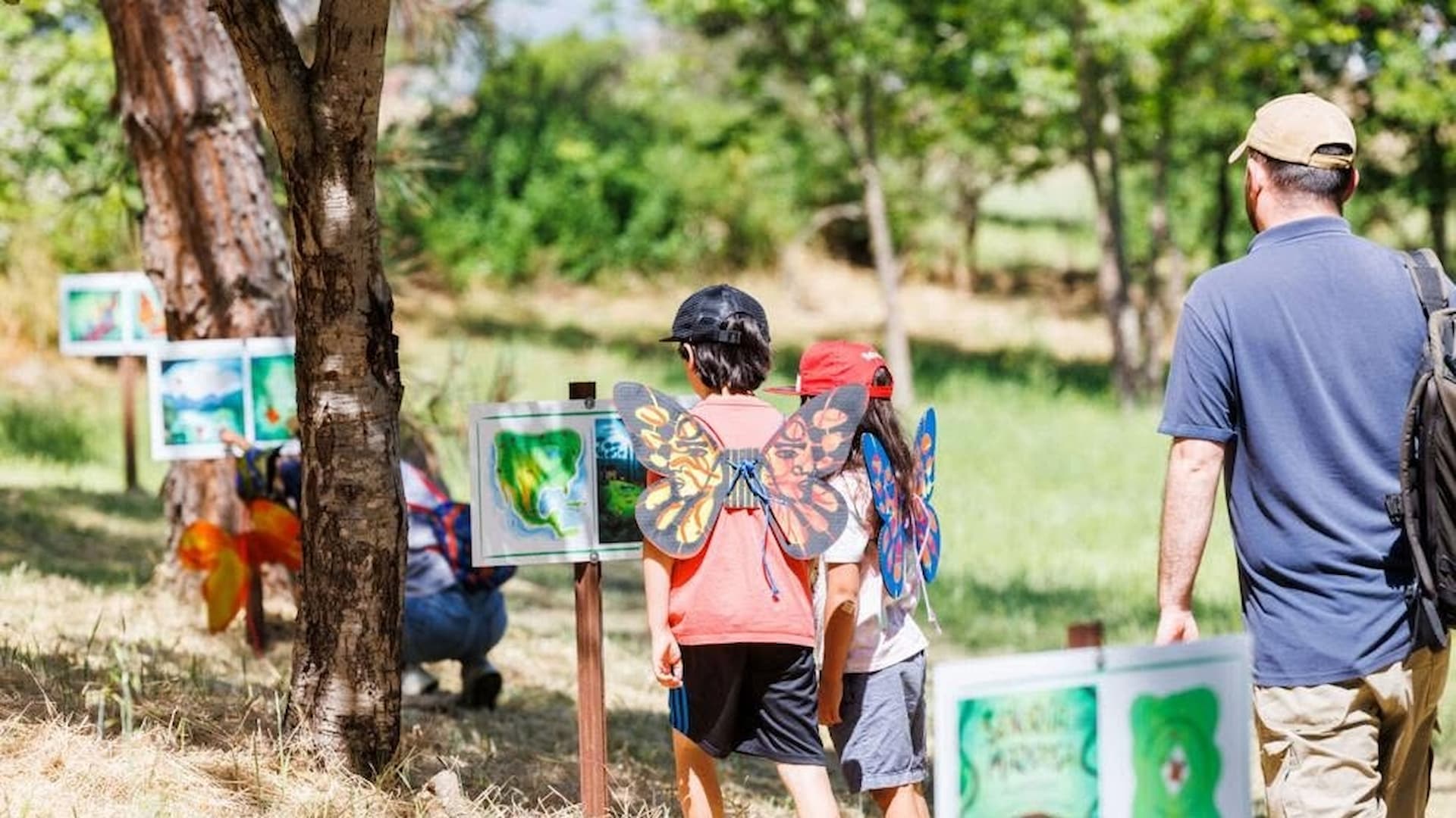 Children with butterfly wings at outdoor art exhibit
