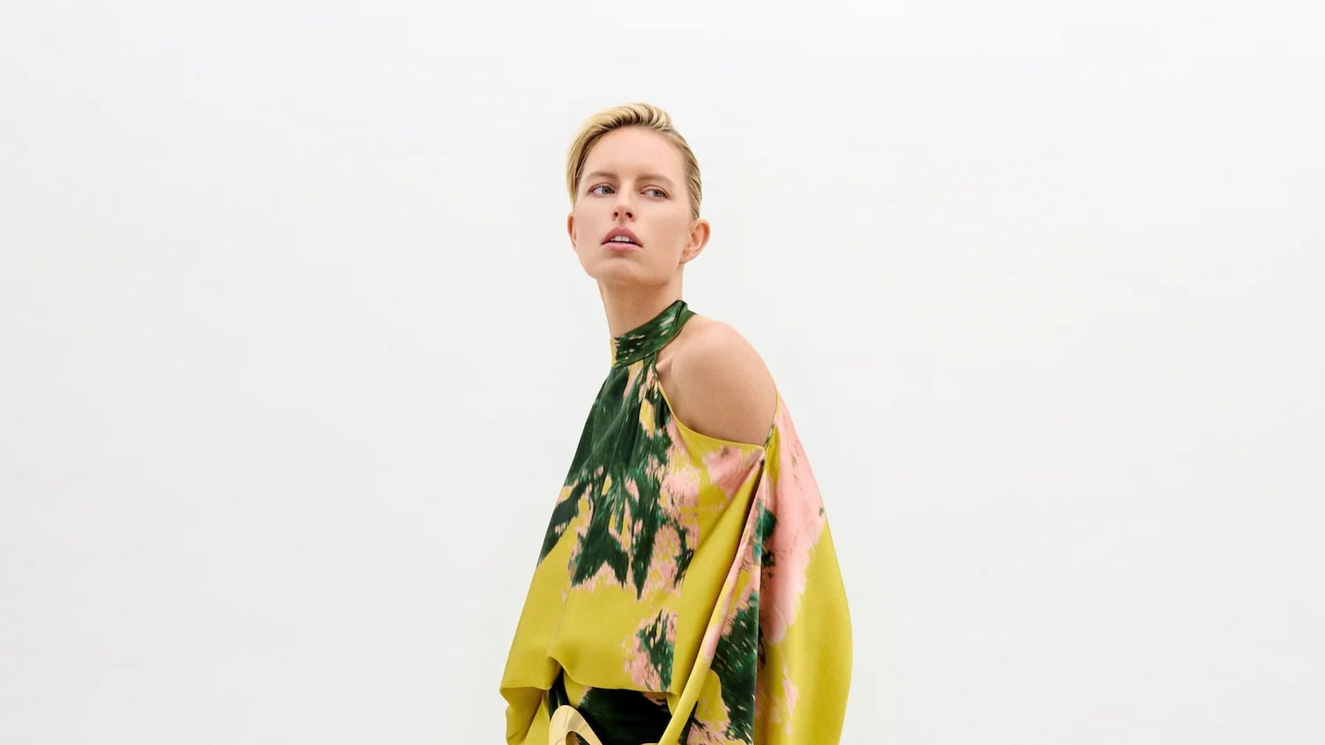 Woman in abstract pattern dress, minimalist background.