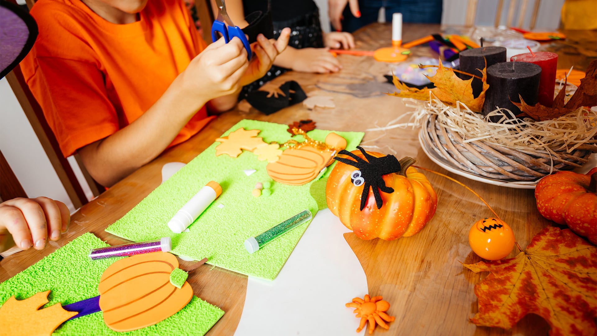 Children crafting Halloween pumpkin and spider decorations at table