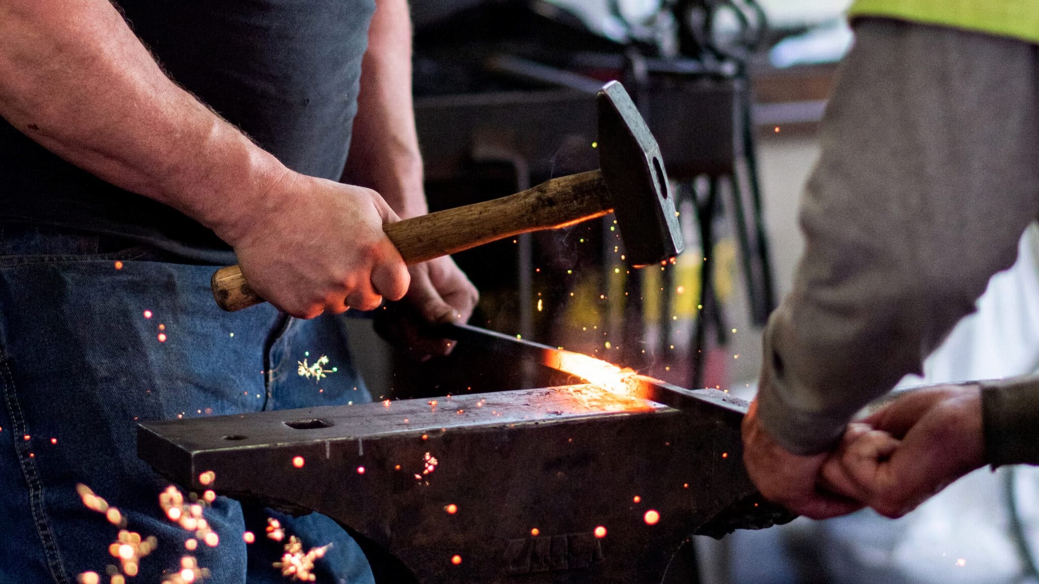 Blacksmith hammering glowing metal on anvil