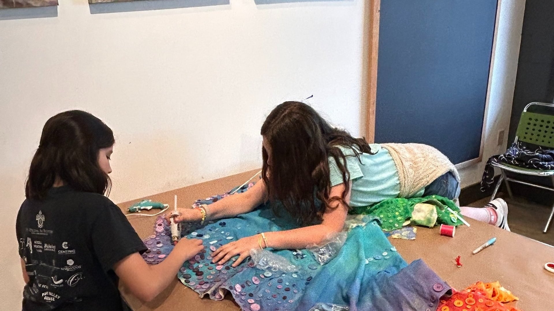 Two girls crafting with fabric and buttons