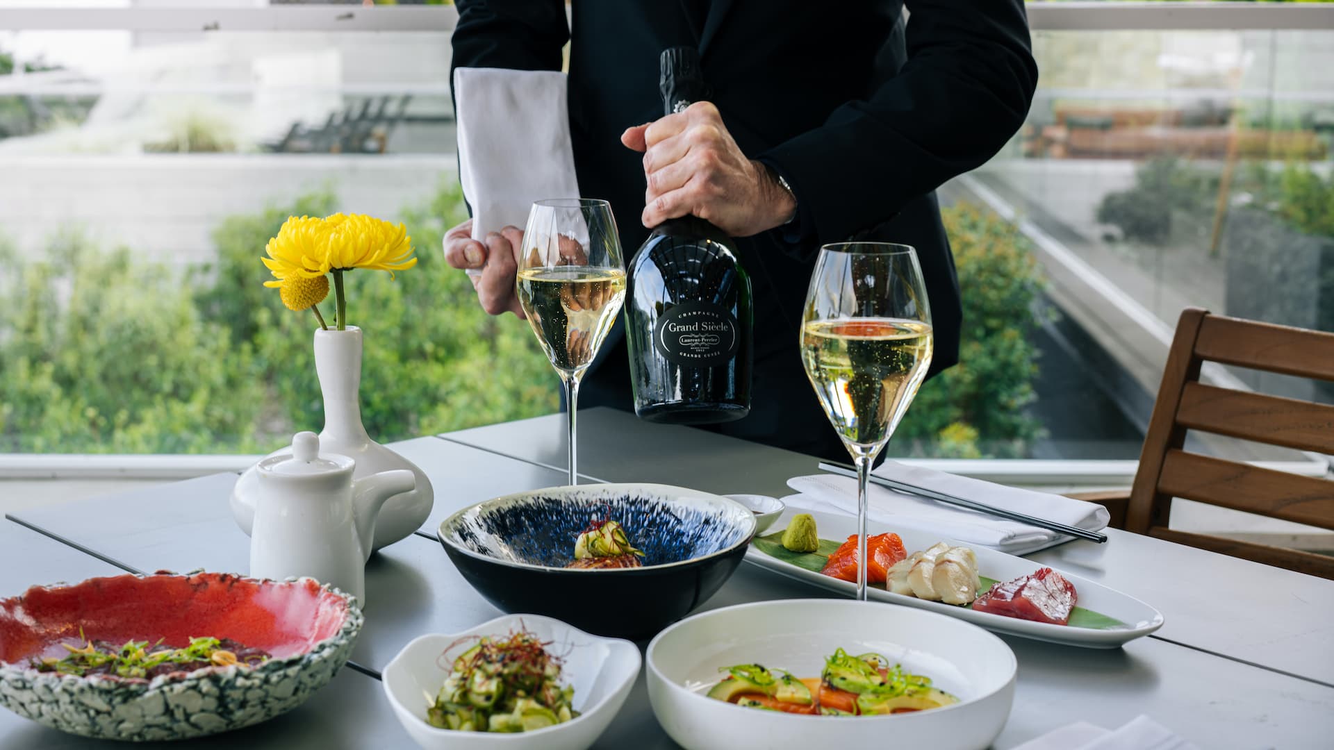 Waiter pouring champagne, with elegant dining setup.