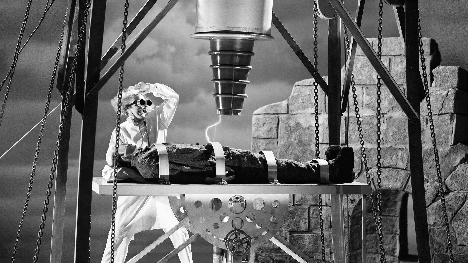 Mad scientist observes strapped man beneath electrical machine