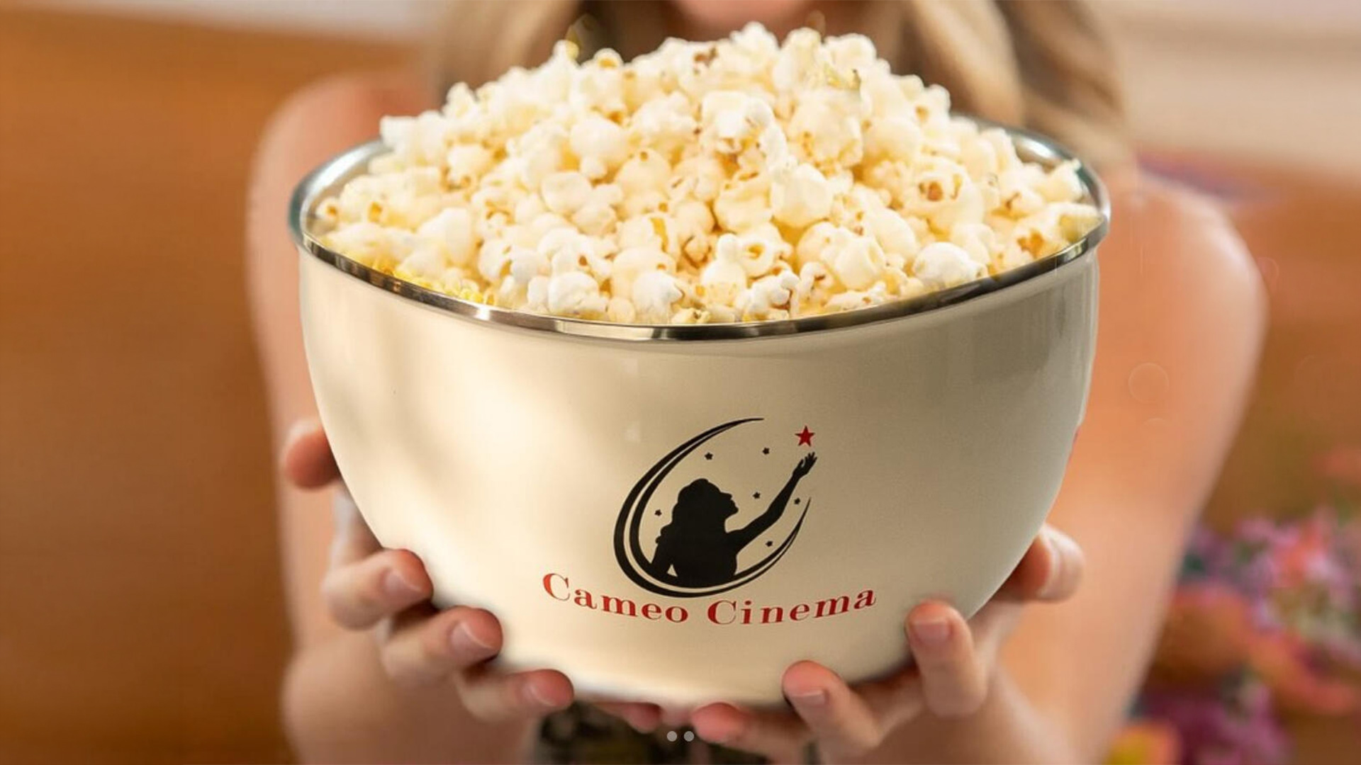 Person holding oversized bowl of popcorn at Cameo Cinema