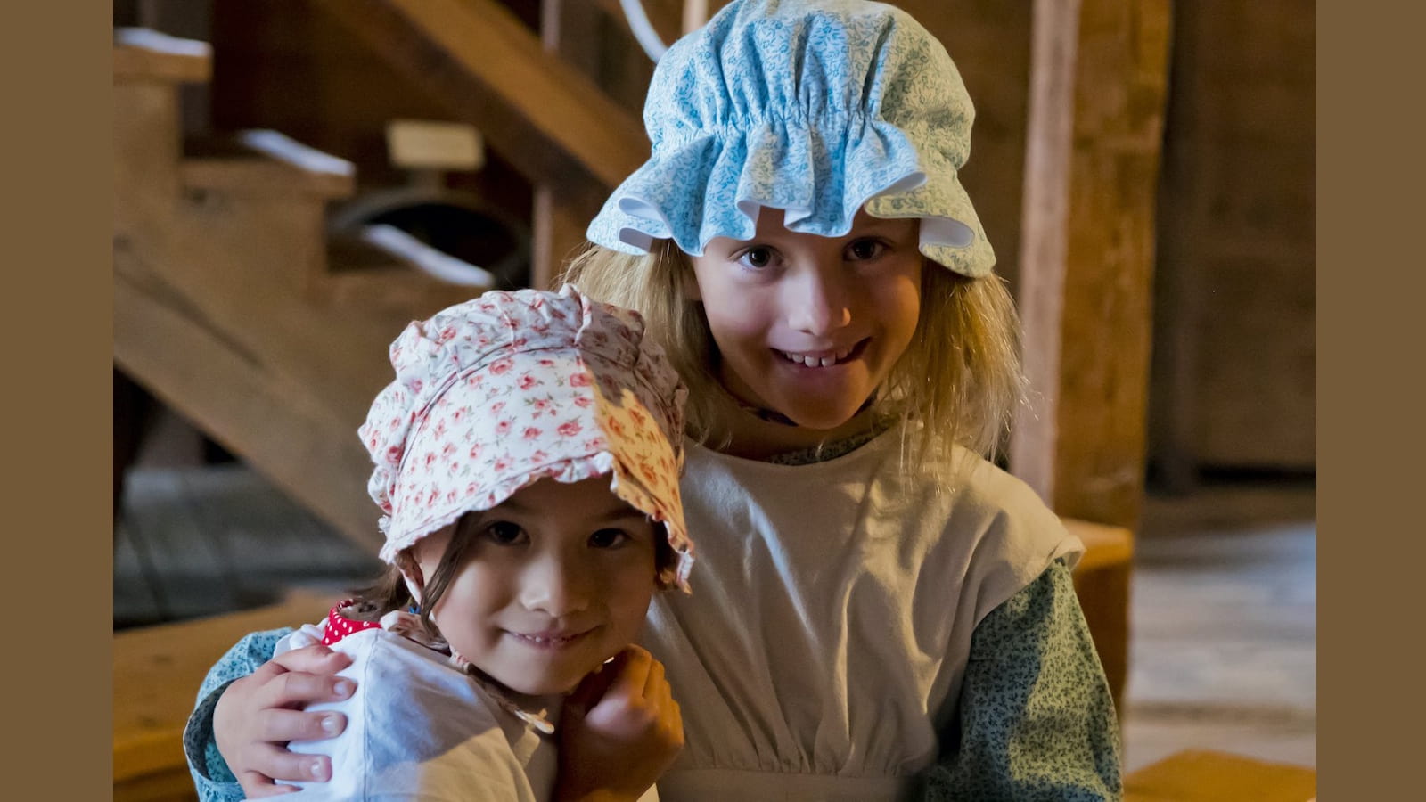 Two children in vintage bonnets and dresses.