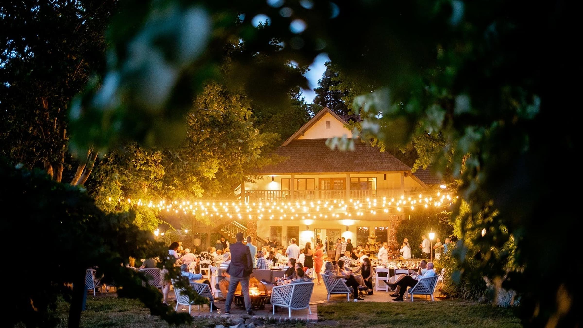 Outdoor evening party with string lights and guests.