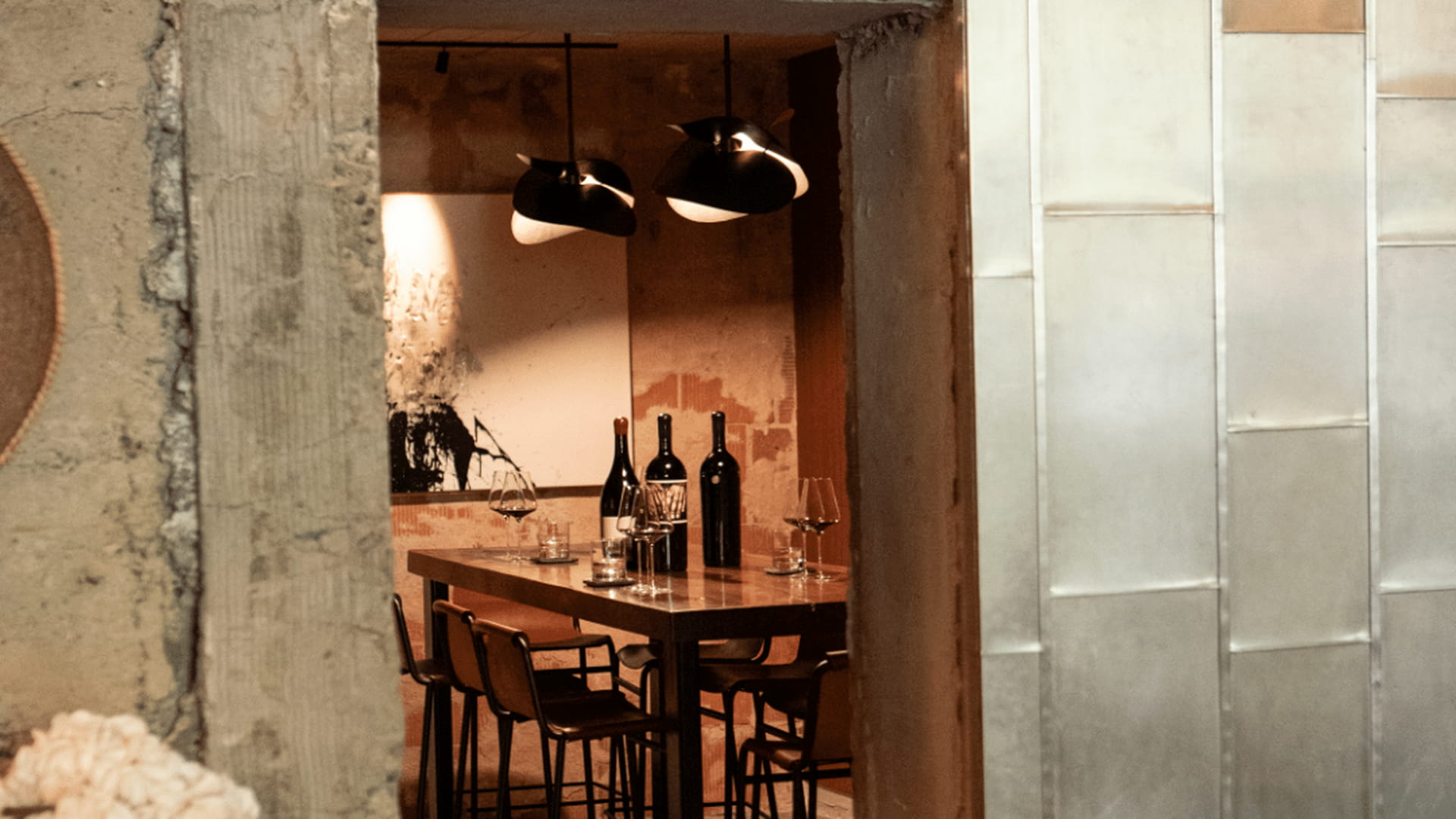 Cozy restaurant interior with wine bottles on table.