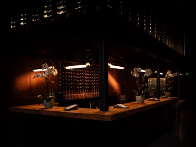 Dimly lit upscale bar counter with orchids and wine display
