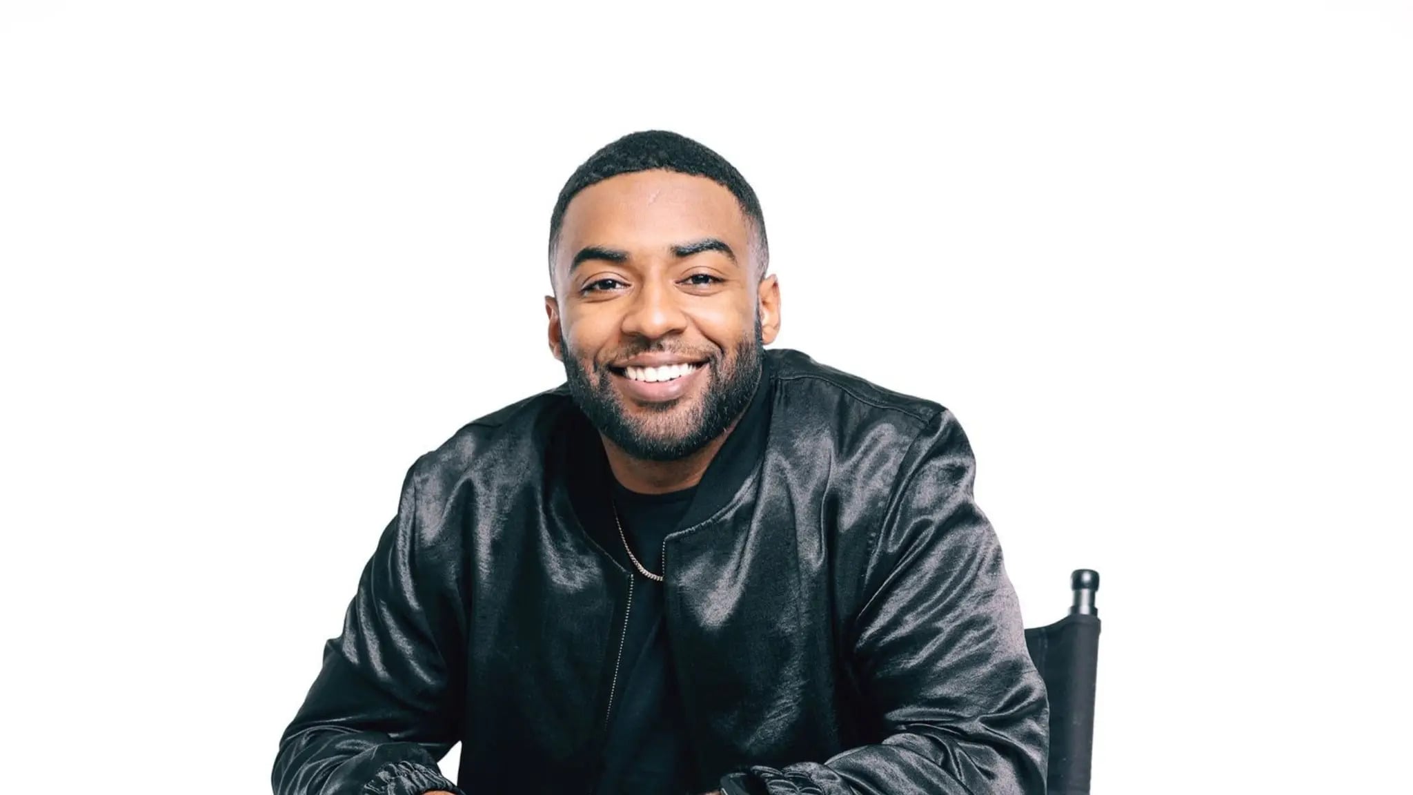 Smiling man in black jacket against gray background