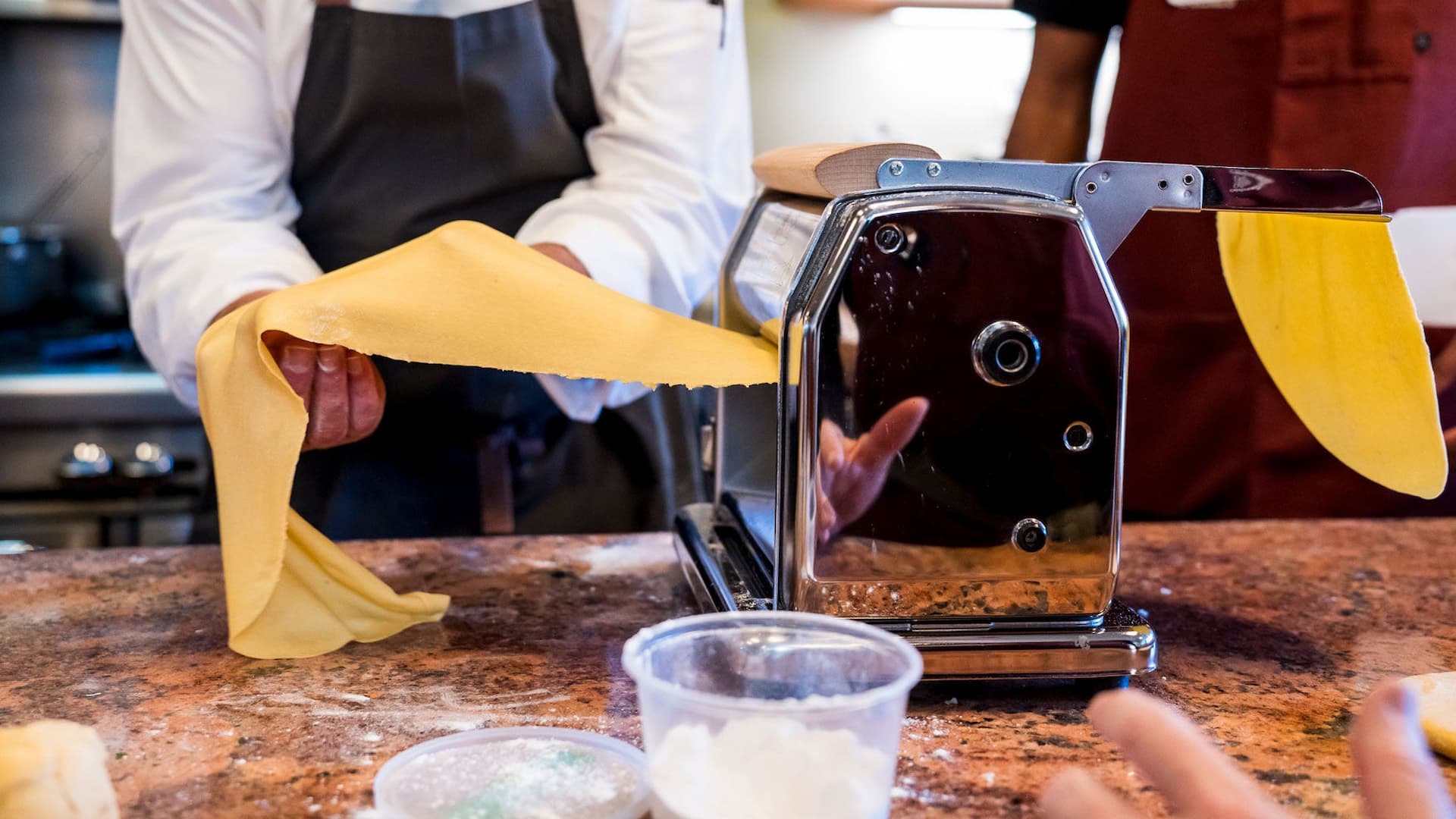 Person making fresh pasta with pasta machine.