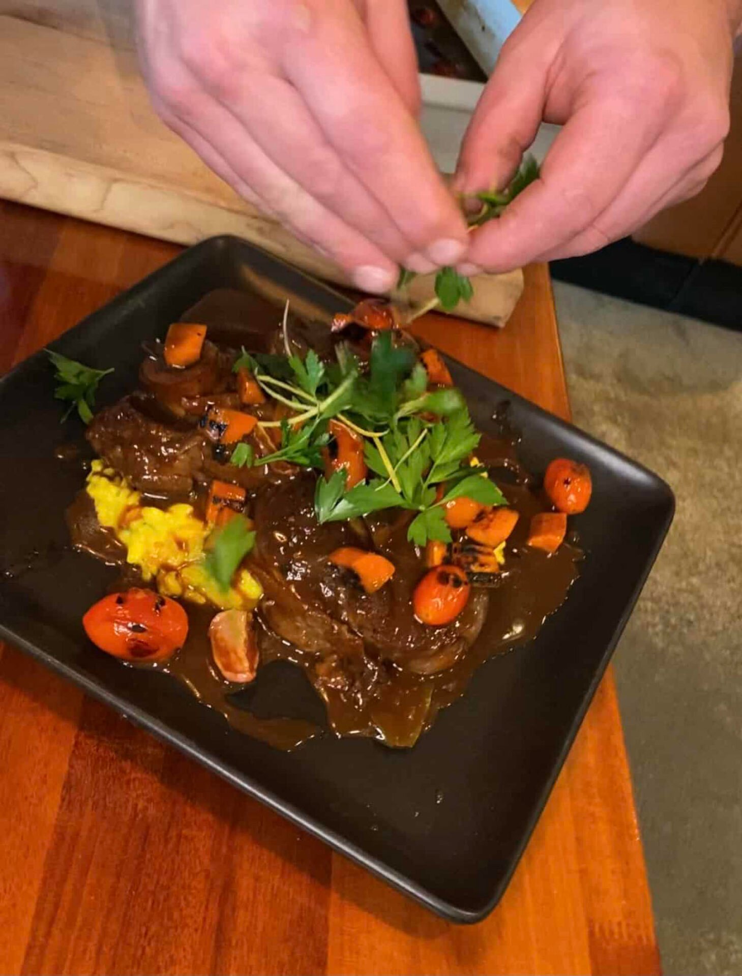 Chef garnishing beef stew with fresh parsley.