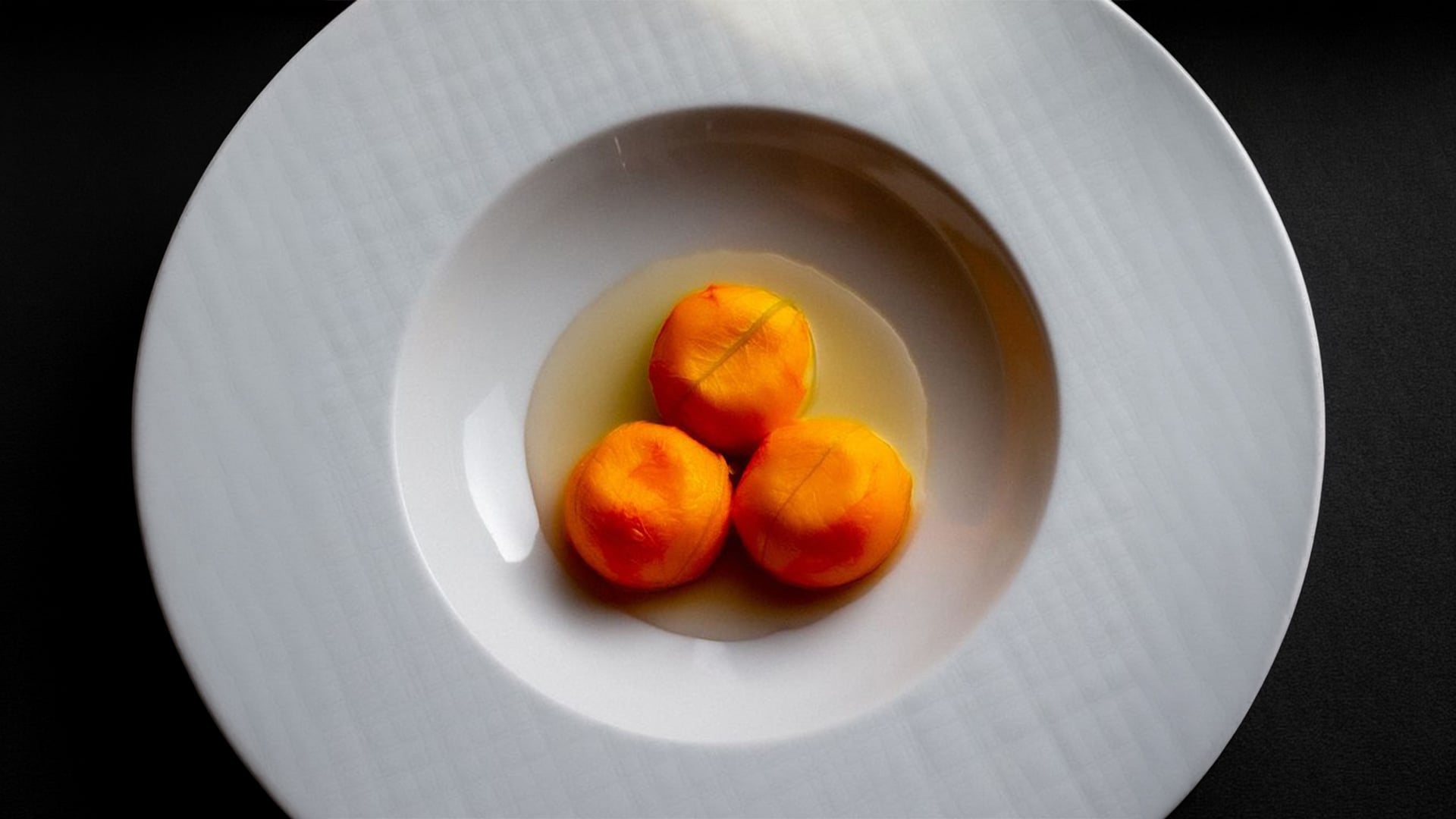 Three peeled tomatoes in white bowl
