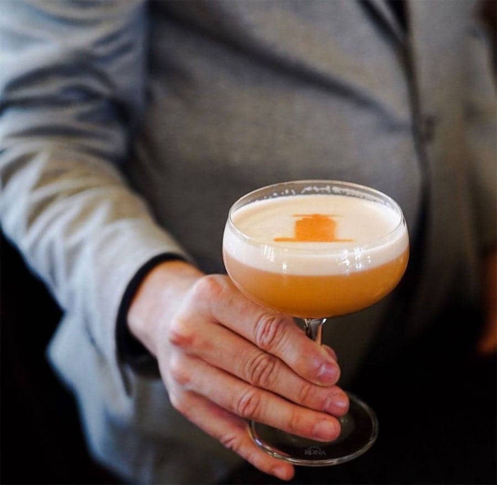 Person holding a cocktail glass with foam.
