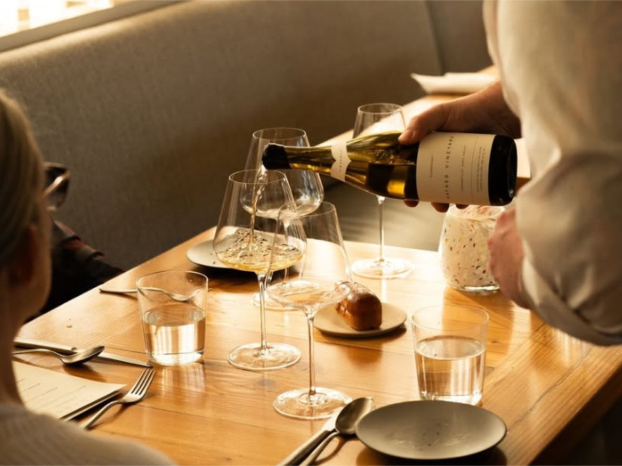 Server pouring white wine at restaurant table
