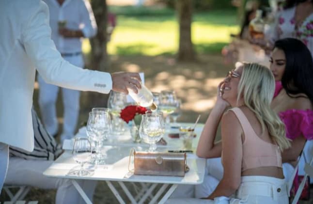 Man pouring champagne at outdoor garden party